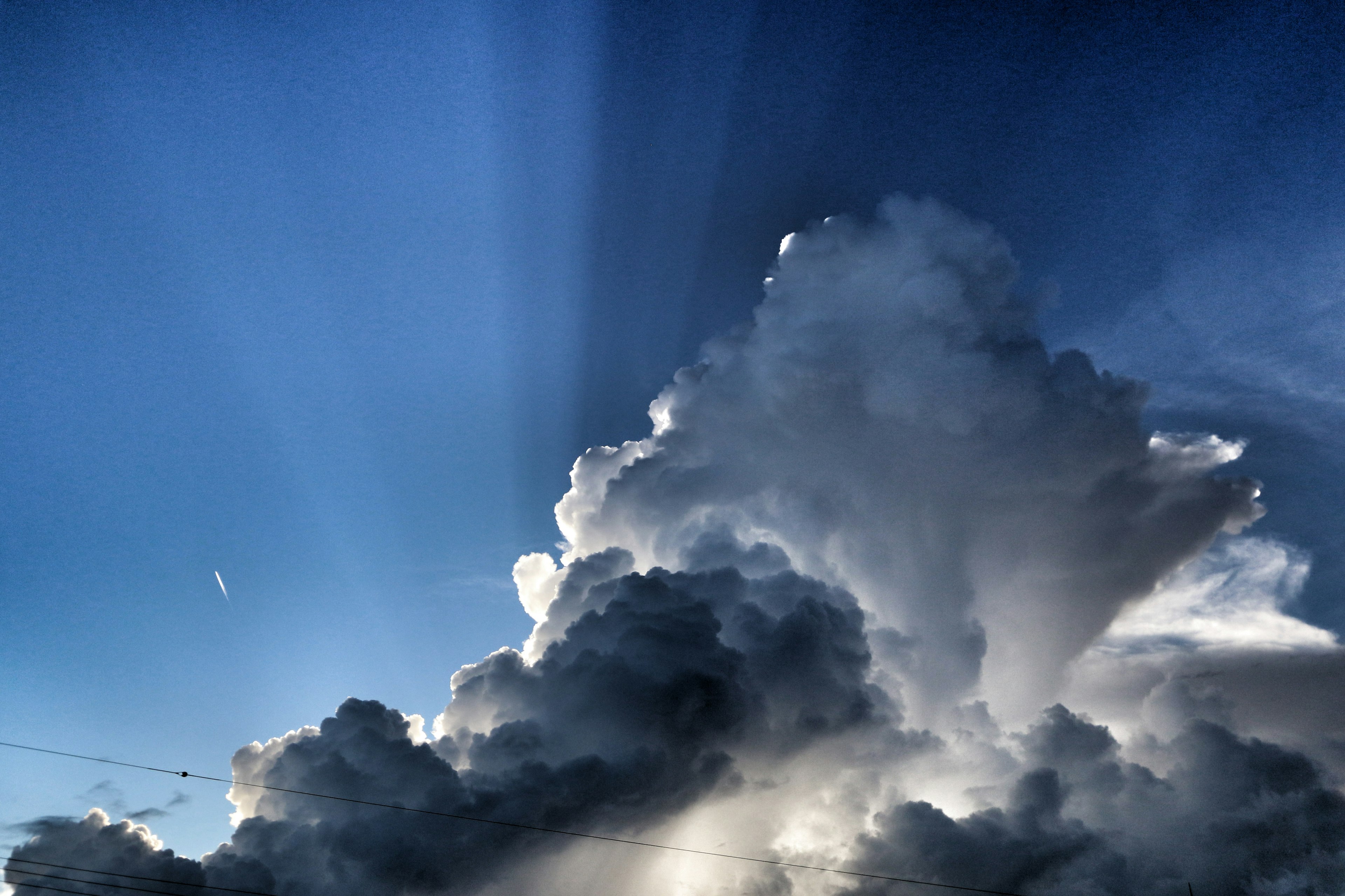 青空に浮かぶ厚い雲と光の筋