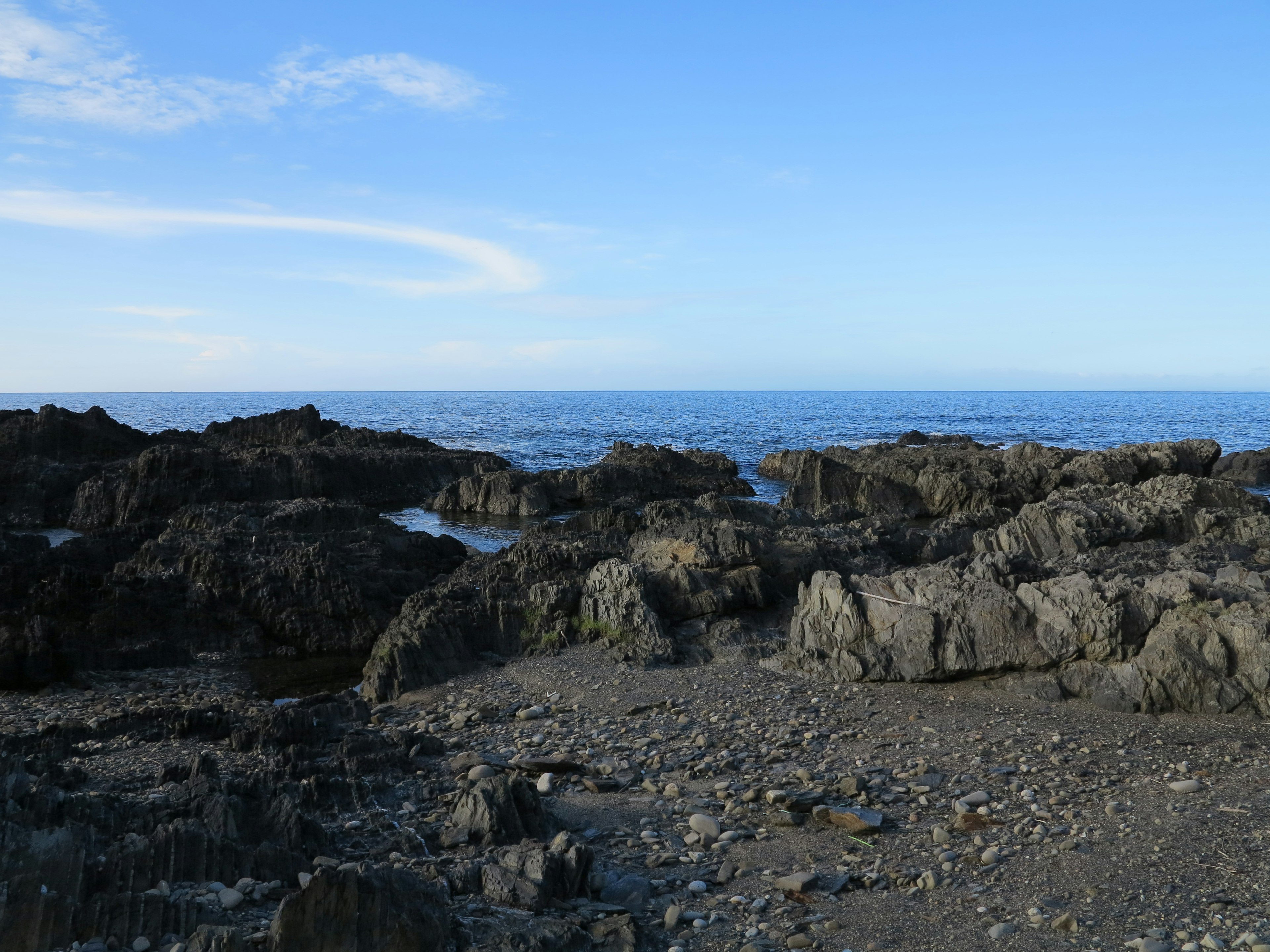 Rocky shoreline with blue sky and ocean in the background