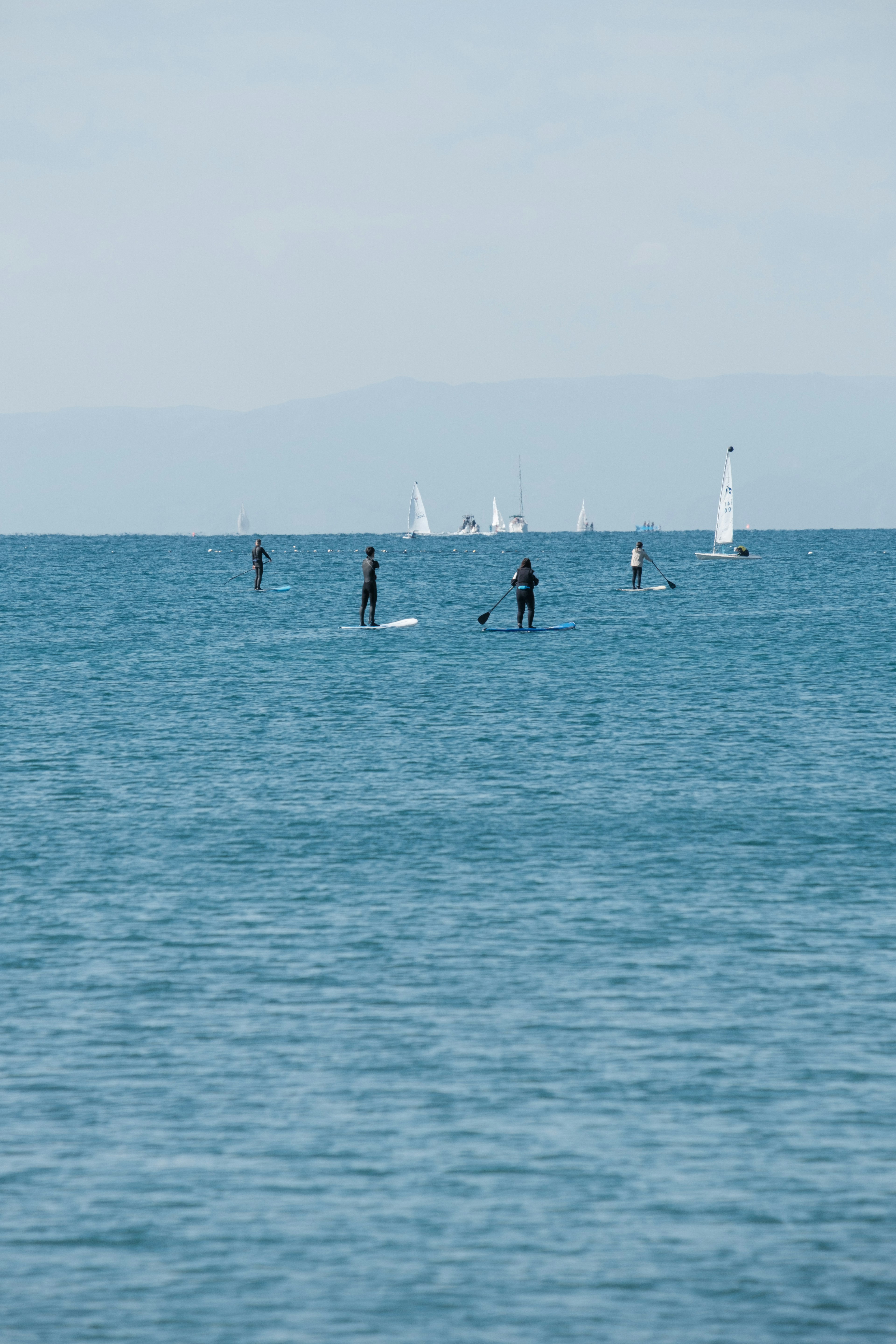 Menschen genießen Stand-Up-Paddleboarding auf einem blauen Ozean