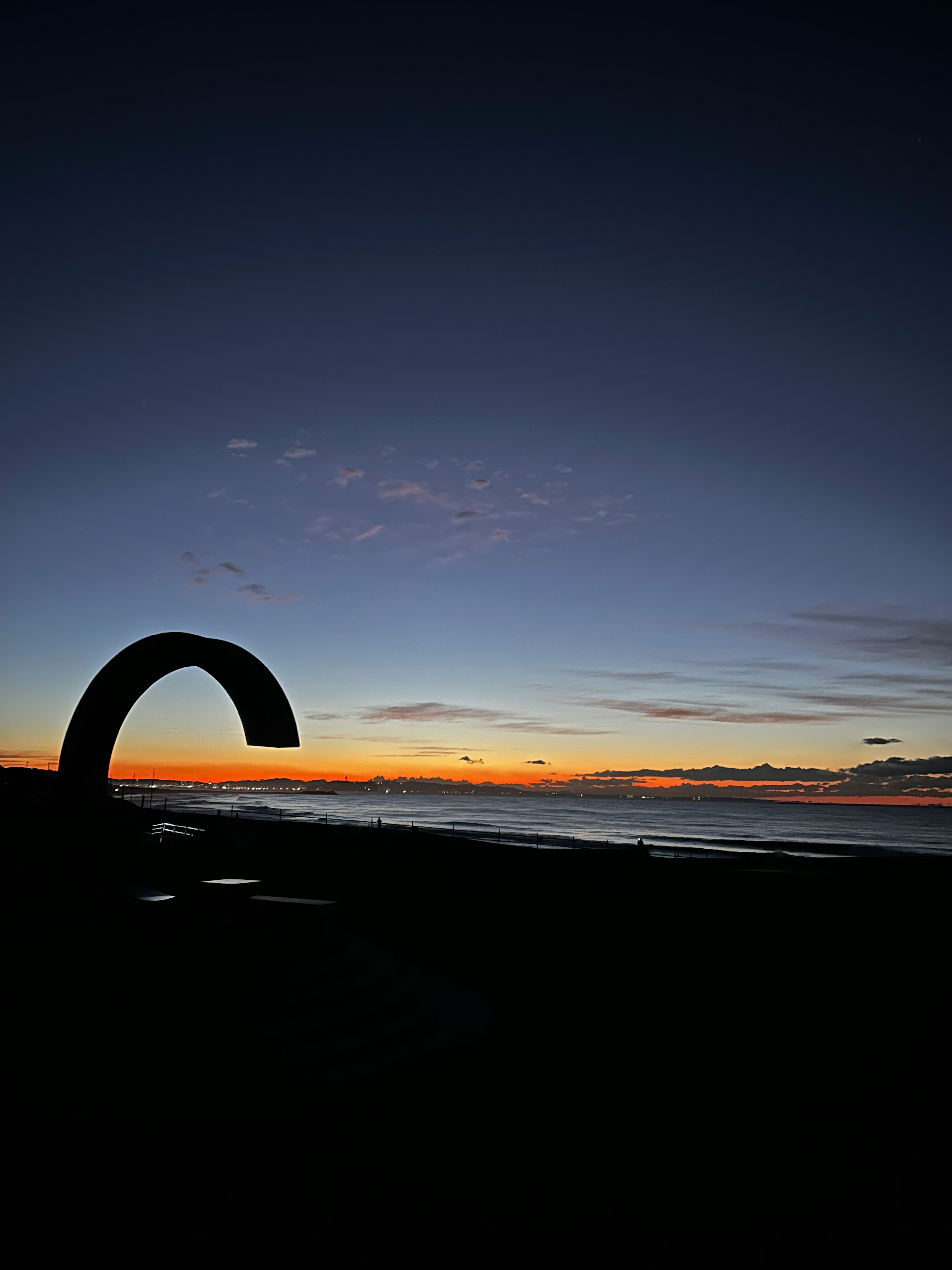 Coastal sunset with an arch-shaped sculpture