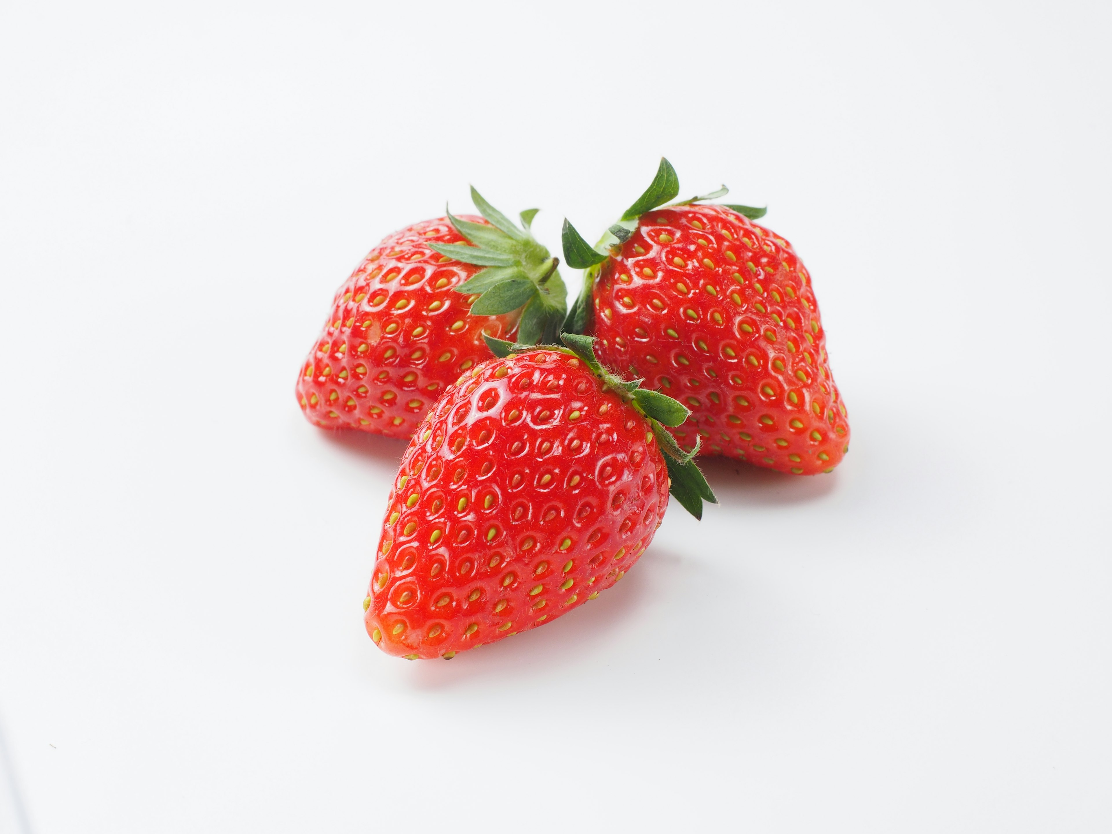 Three fresh strawberries on a white background