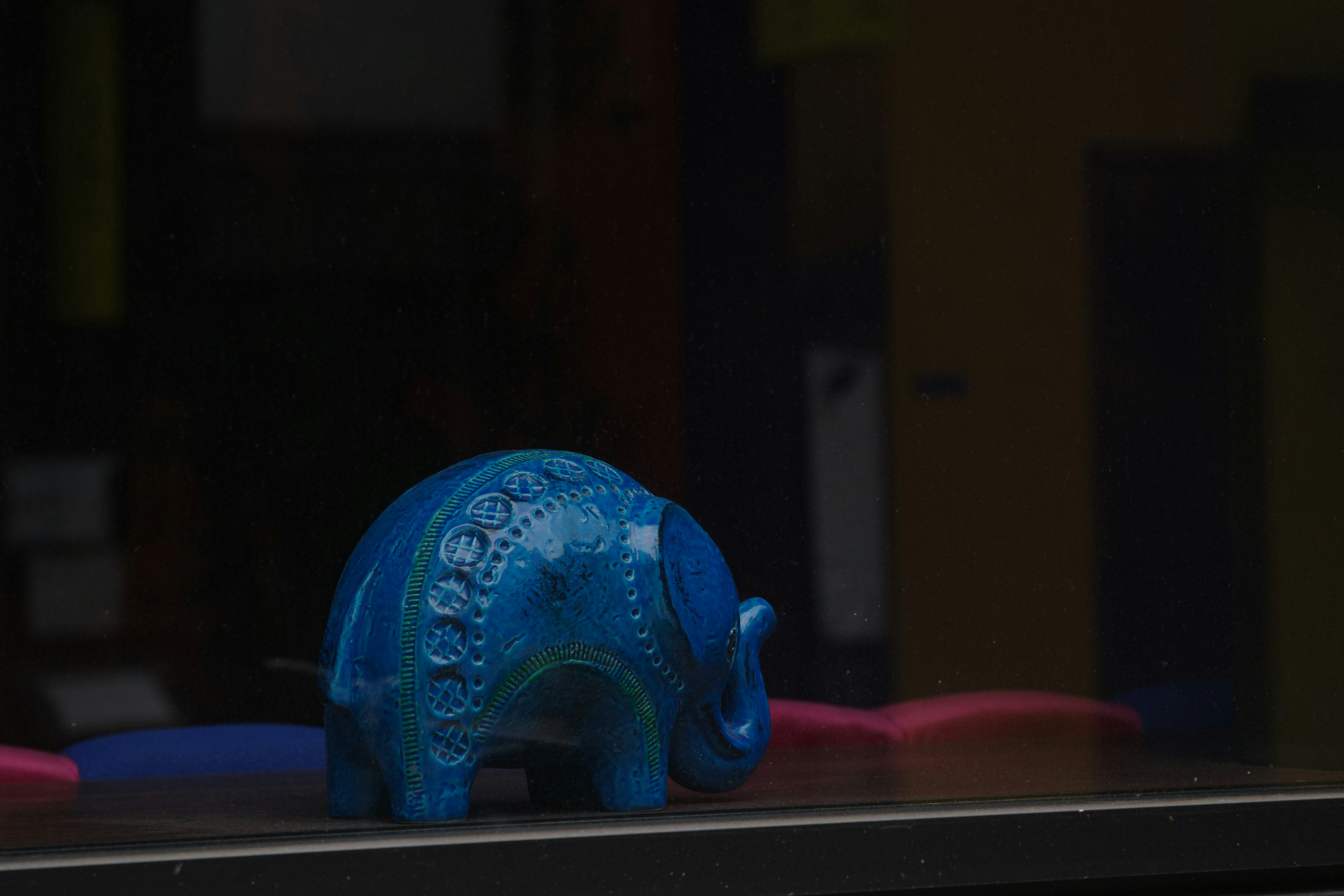 A blue elephant figurine placed by a window