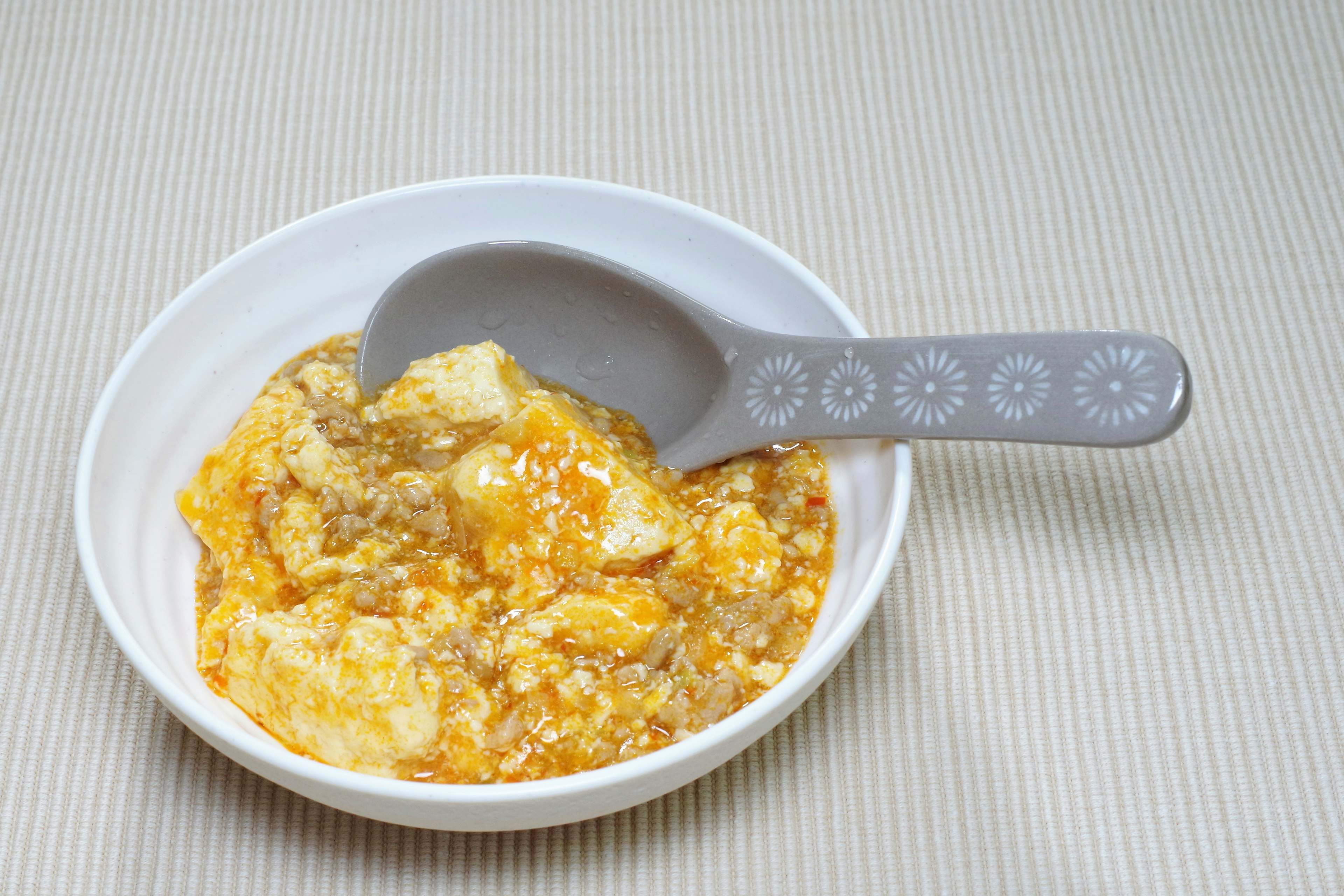 Plato de huevos servido en un bol blanco con una cuchara gris