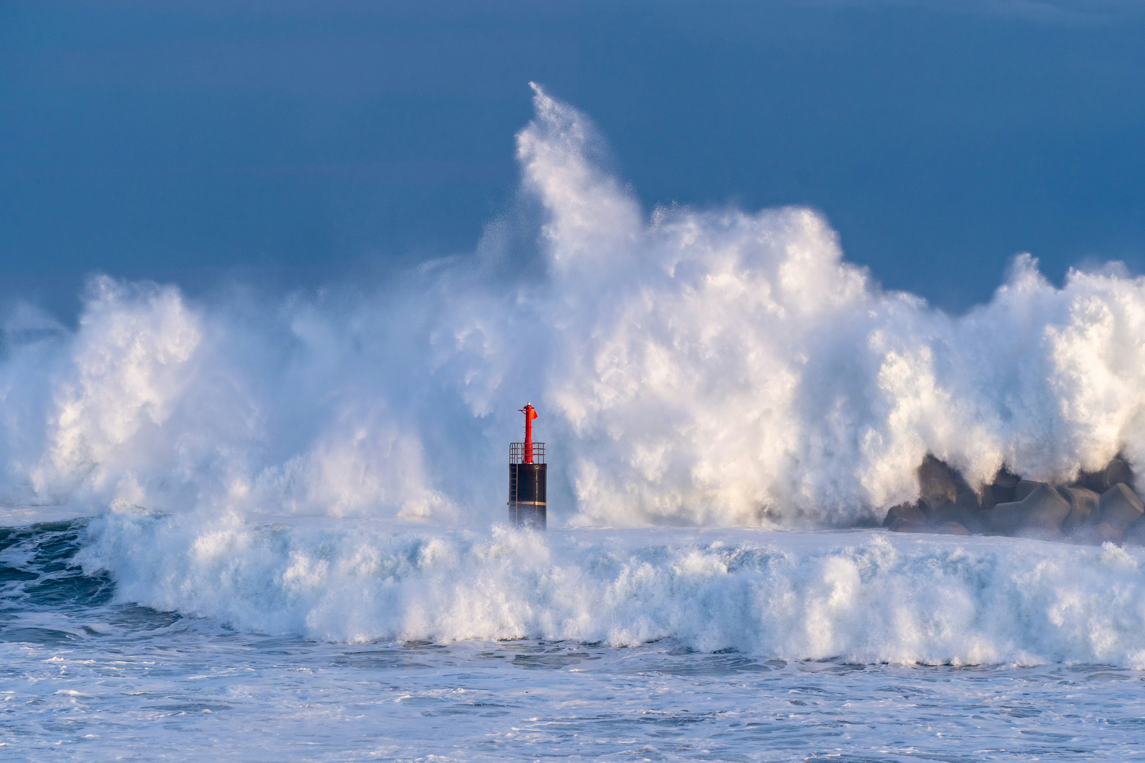 Onde oceaniche che si infrangono contro una boa nera e rossa