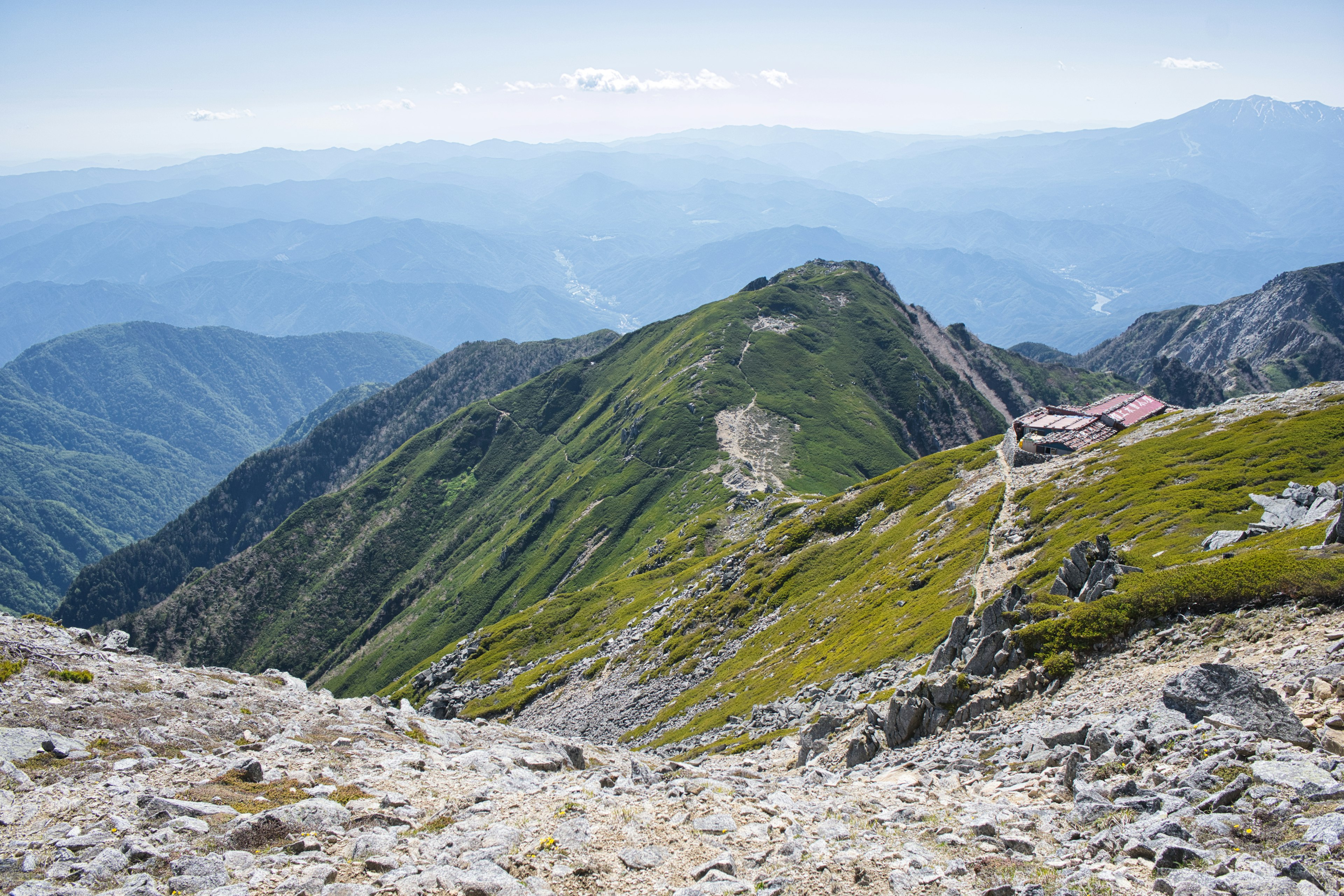 Malersches Berglandschaft mit grünen Hügeln und felsigem Gelände, entfernte blaue Berge