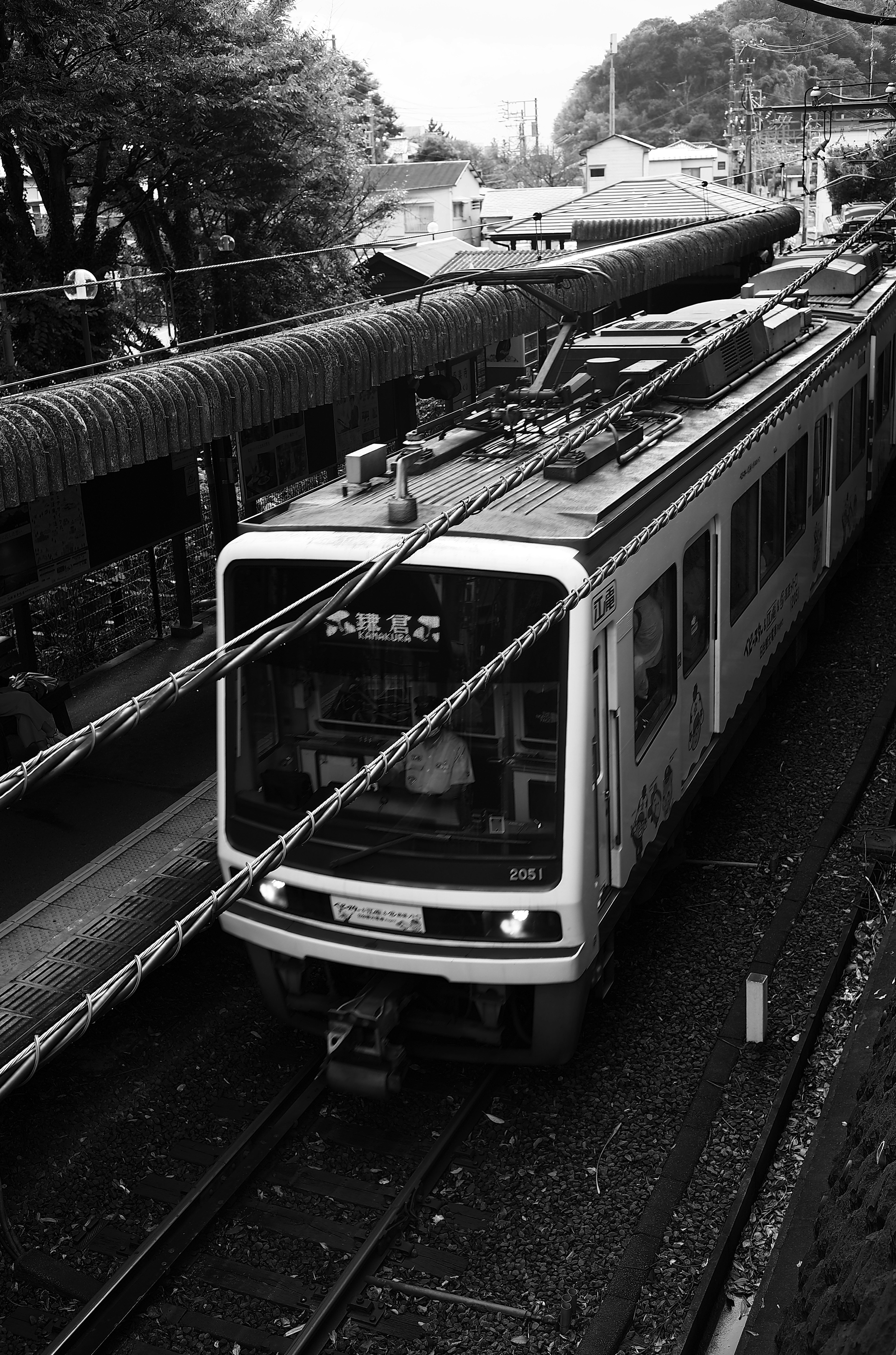 白黒の電車が線路を走る風景駅の屋根が見える