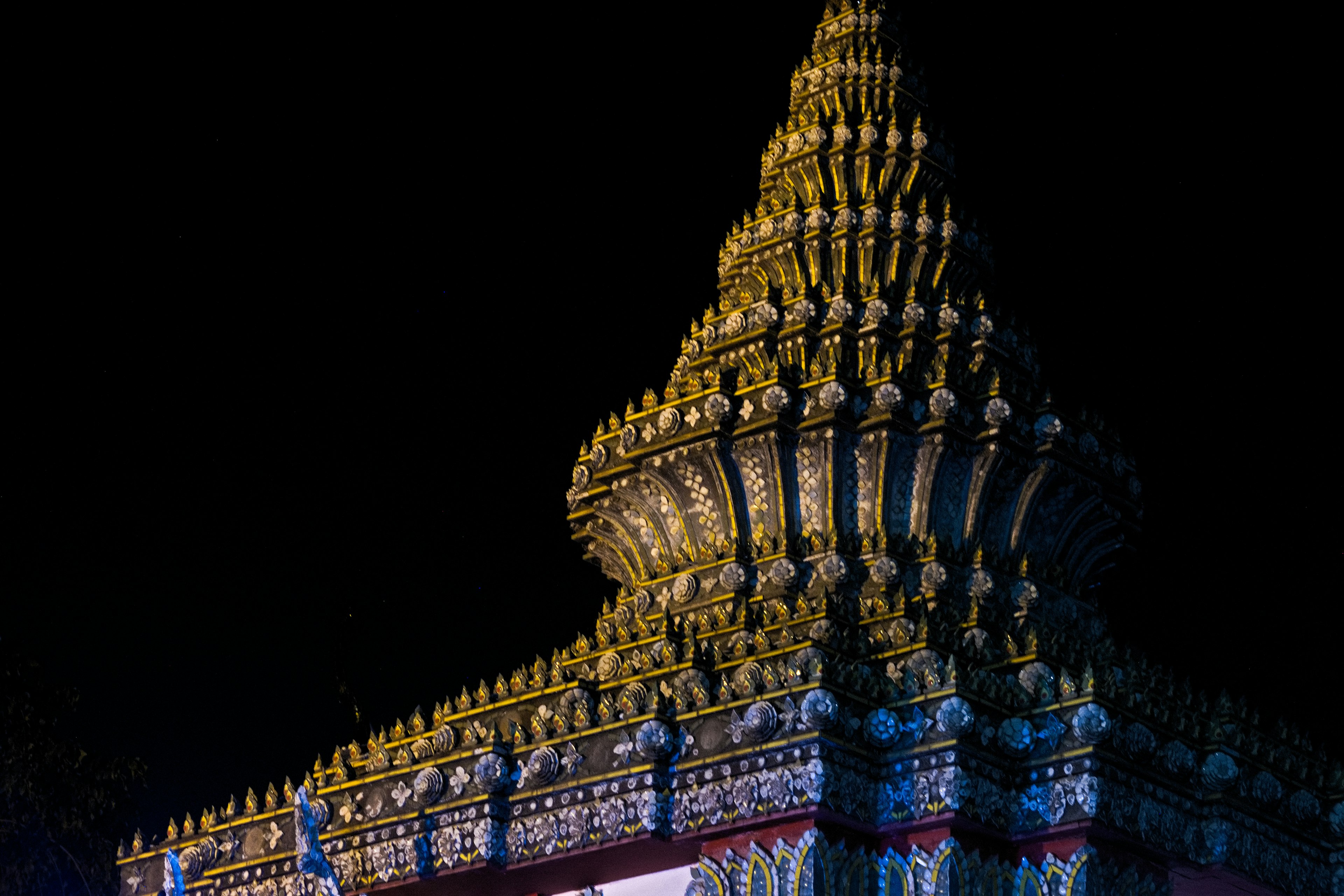 Illuminated golden spire of a temple at night