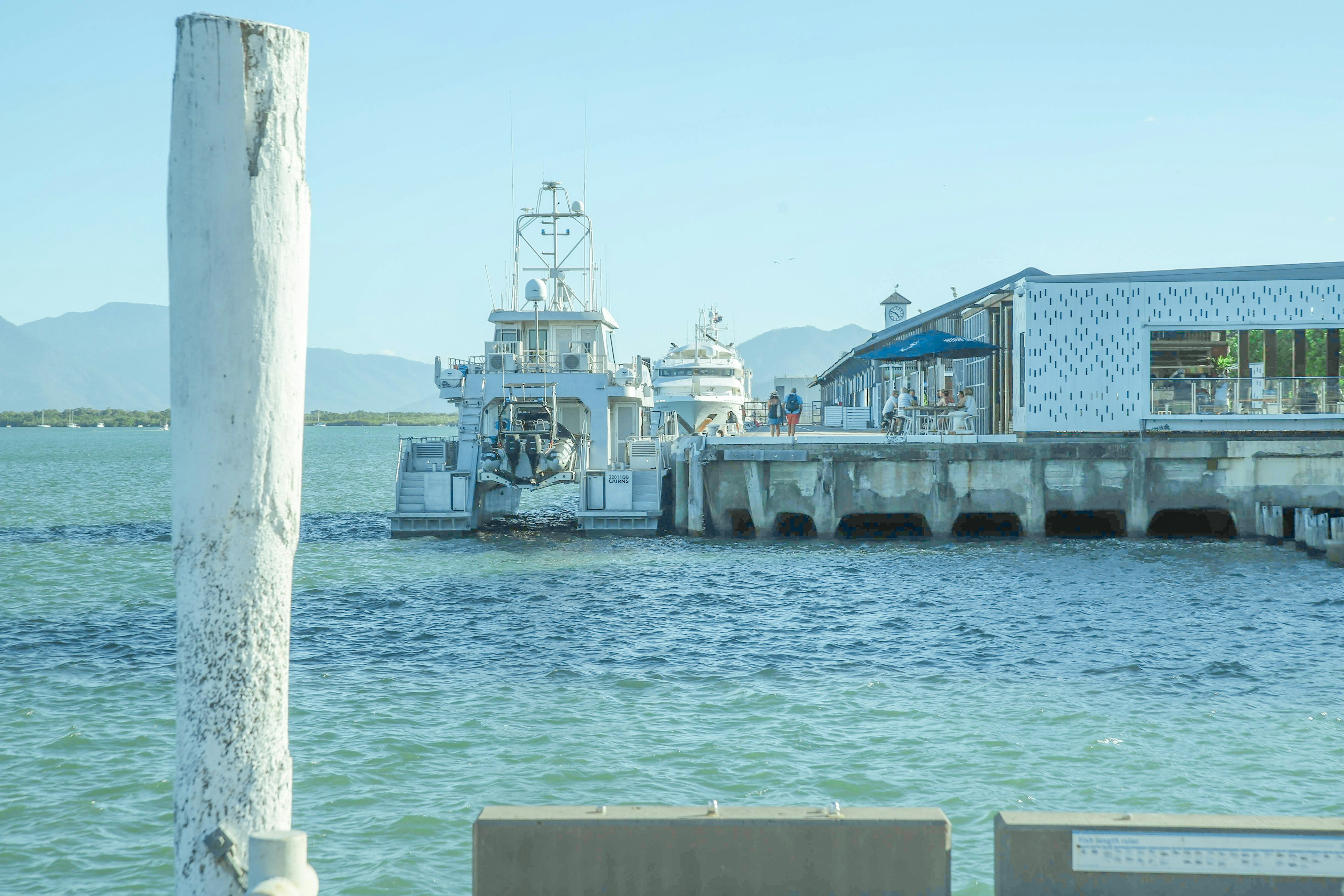 Ein Boot, das sich einem Pier mit einem modernen Gebäude neben dem Wasser nähert