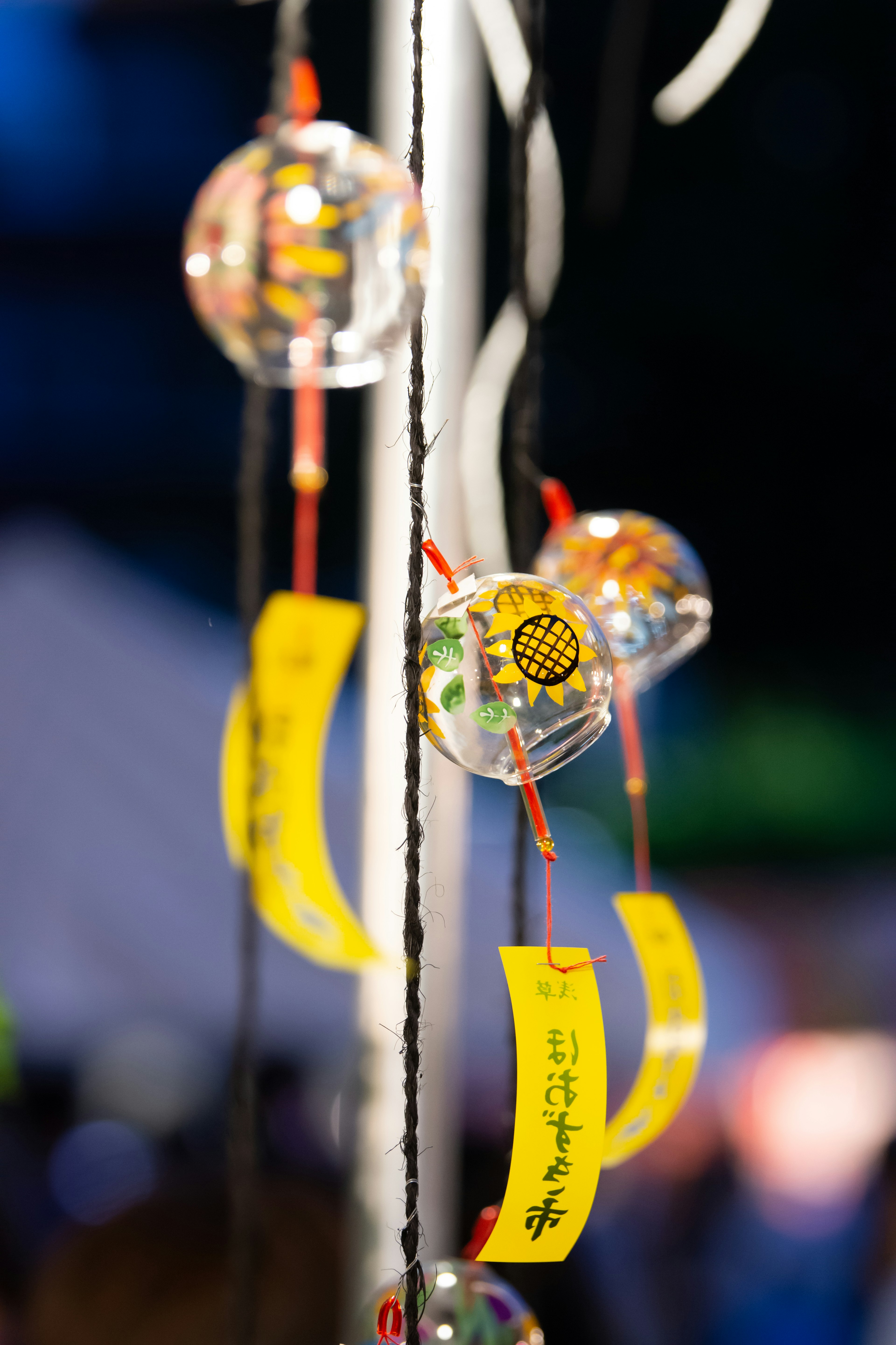 Bunte Windspiele mit gelben Etiketten, die auf einem Nachtmarkt hängen