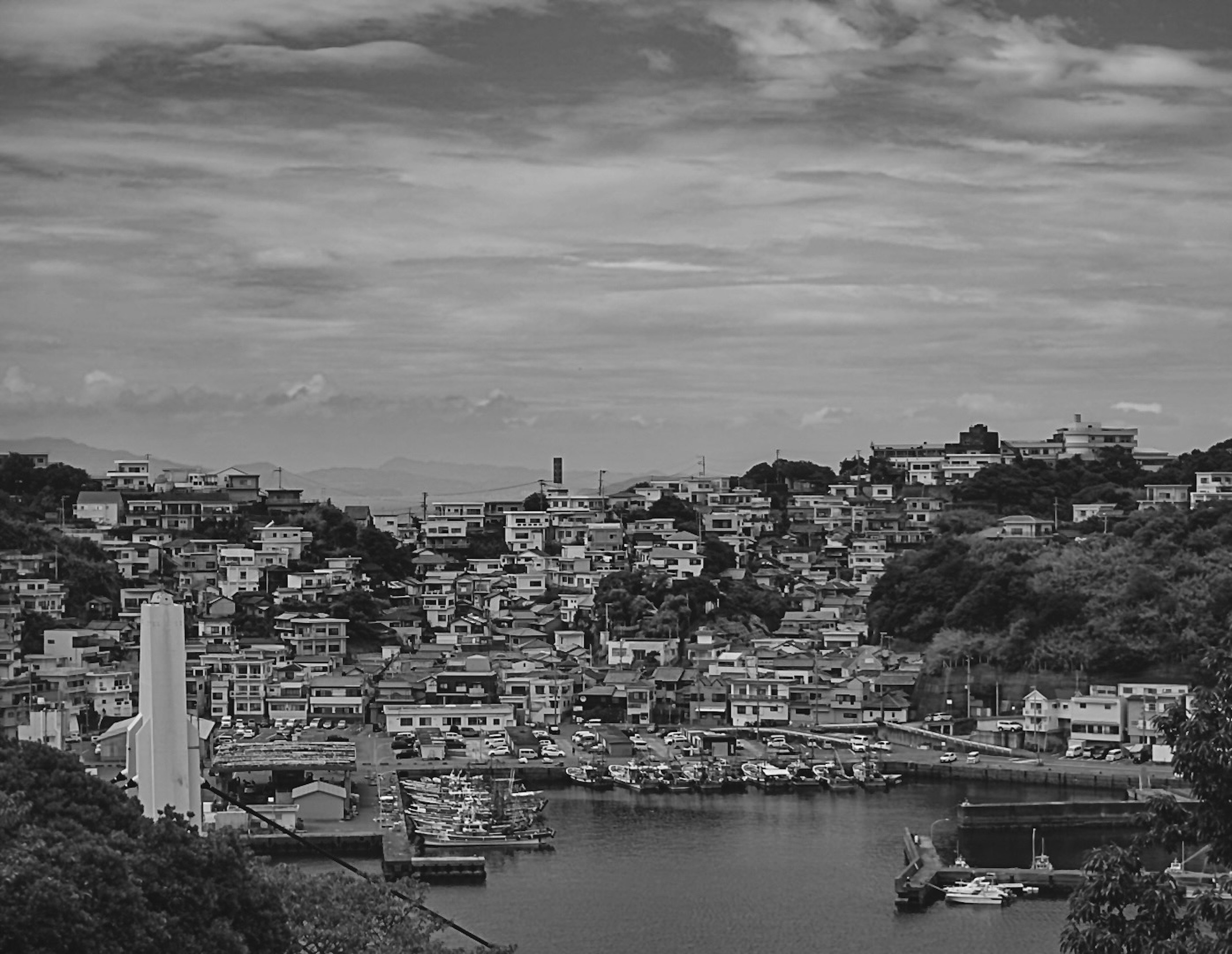 Monochrome view of a coastal town with scattered clouds