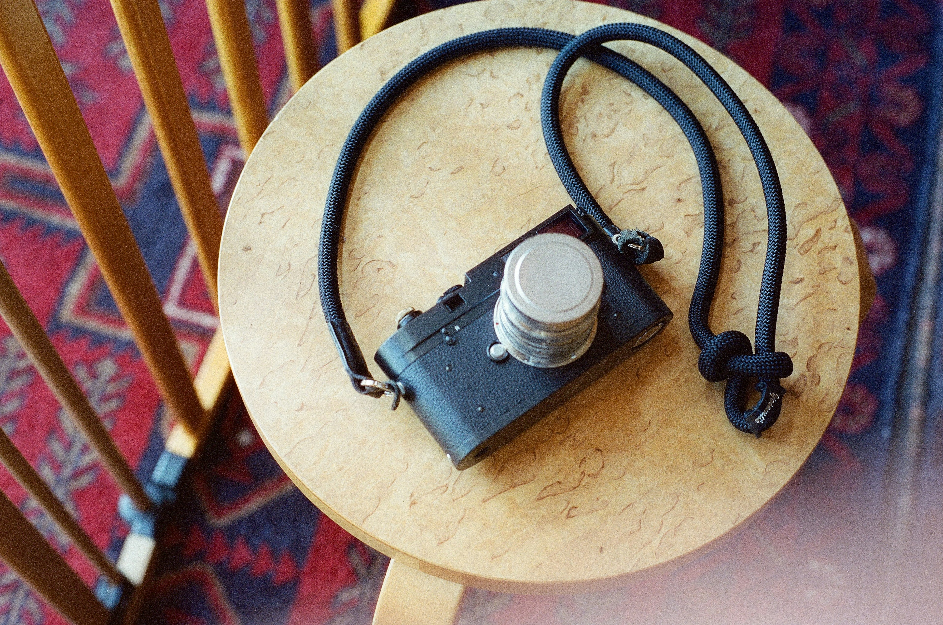 A small camera with a black strap resting on a wooden table