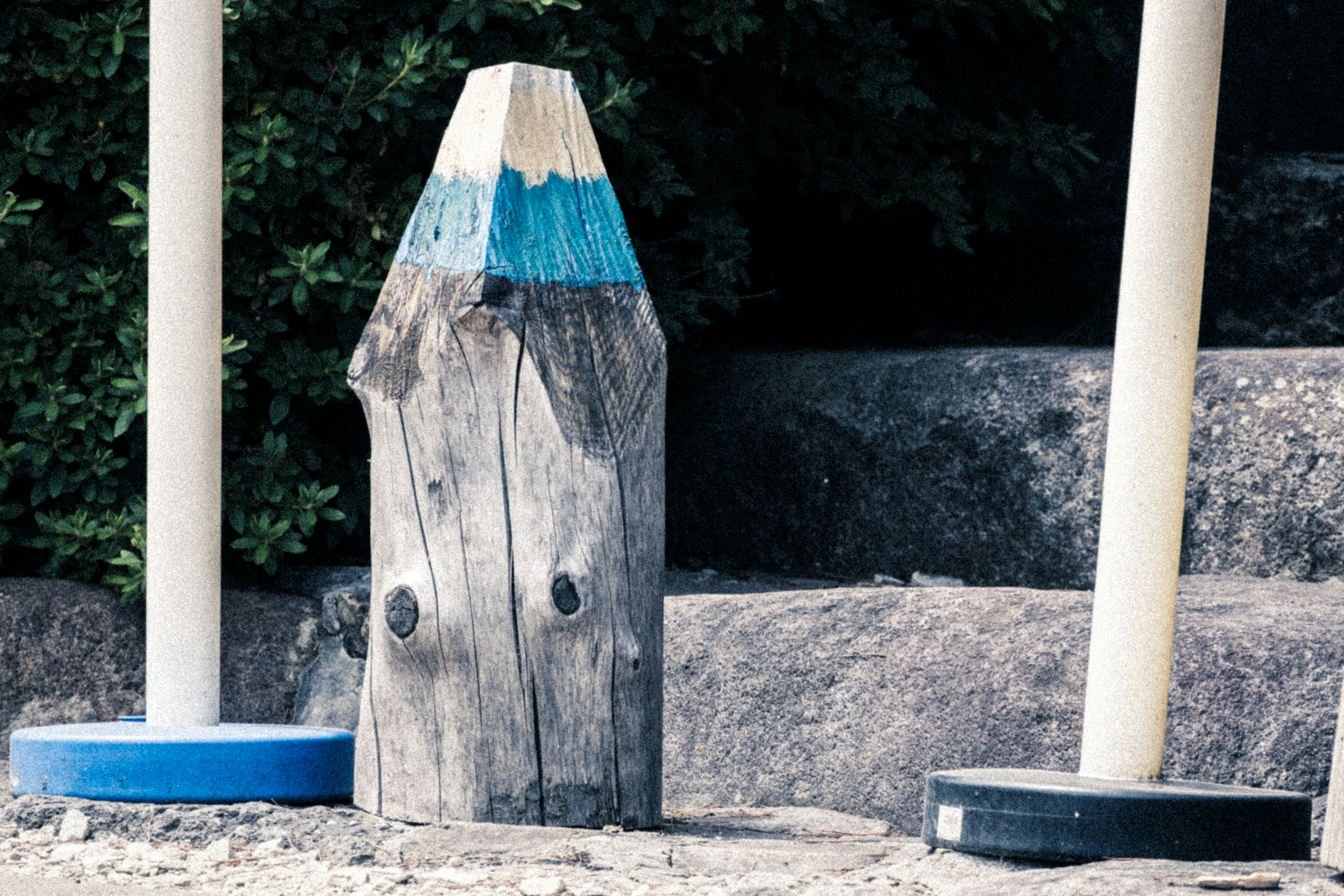 Objet en bois en forme de crayon bleu posé sur des marches en pierre