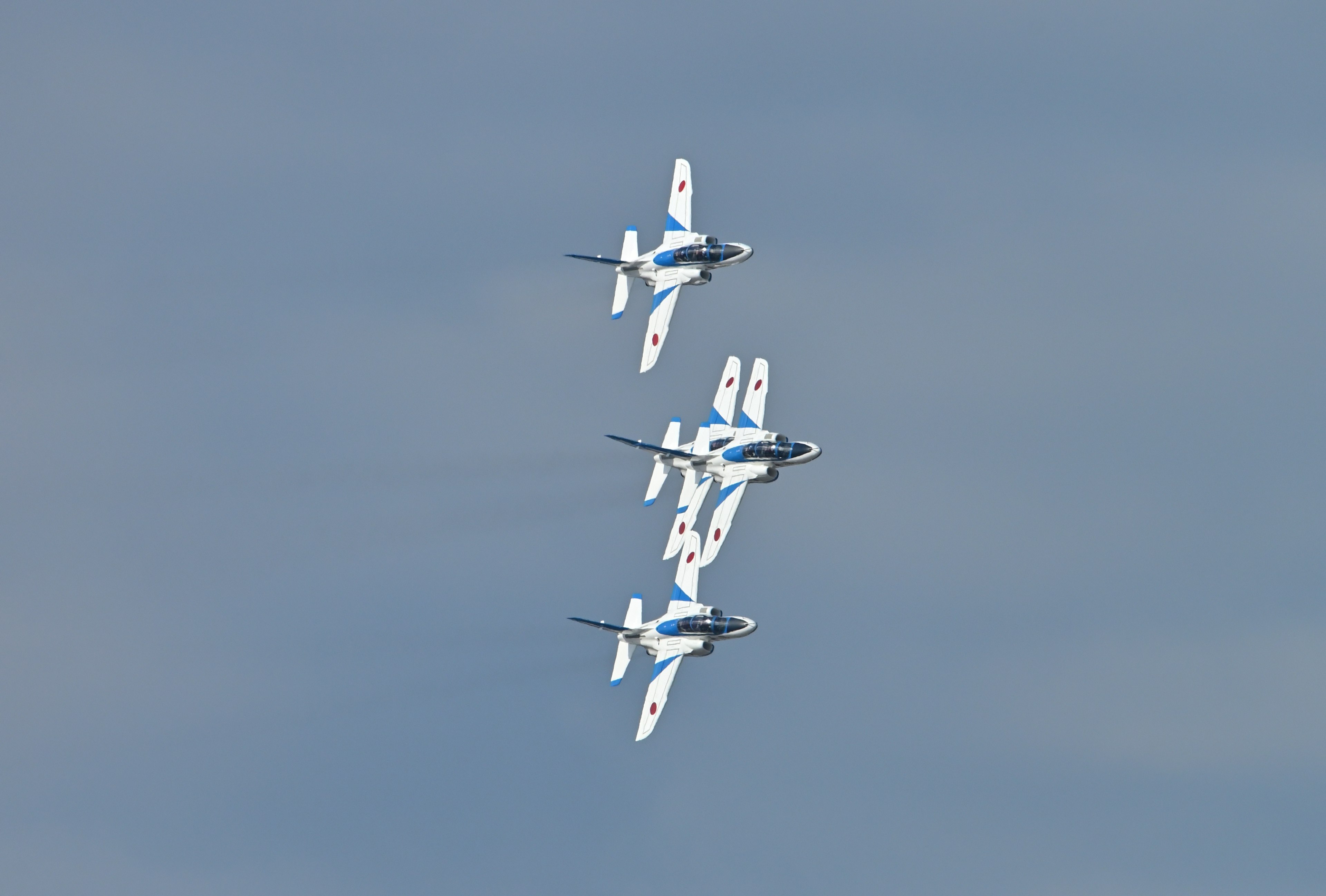 Cuatro aviones acrobáticos realizando un impresionante vuelo en formación contra un cielo azul