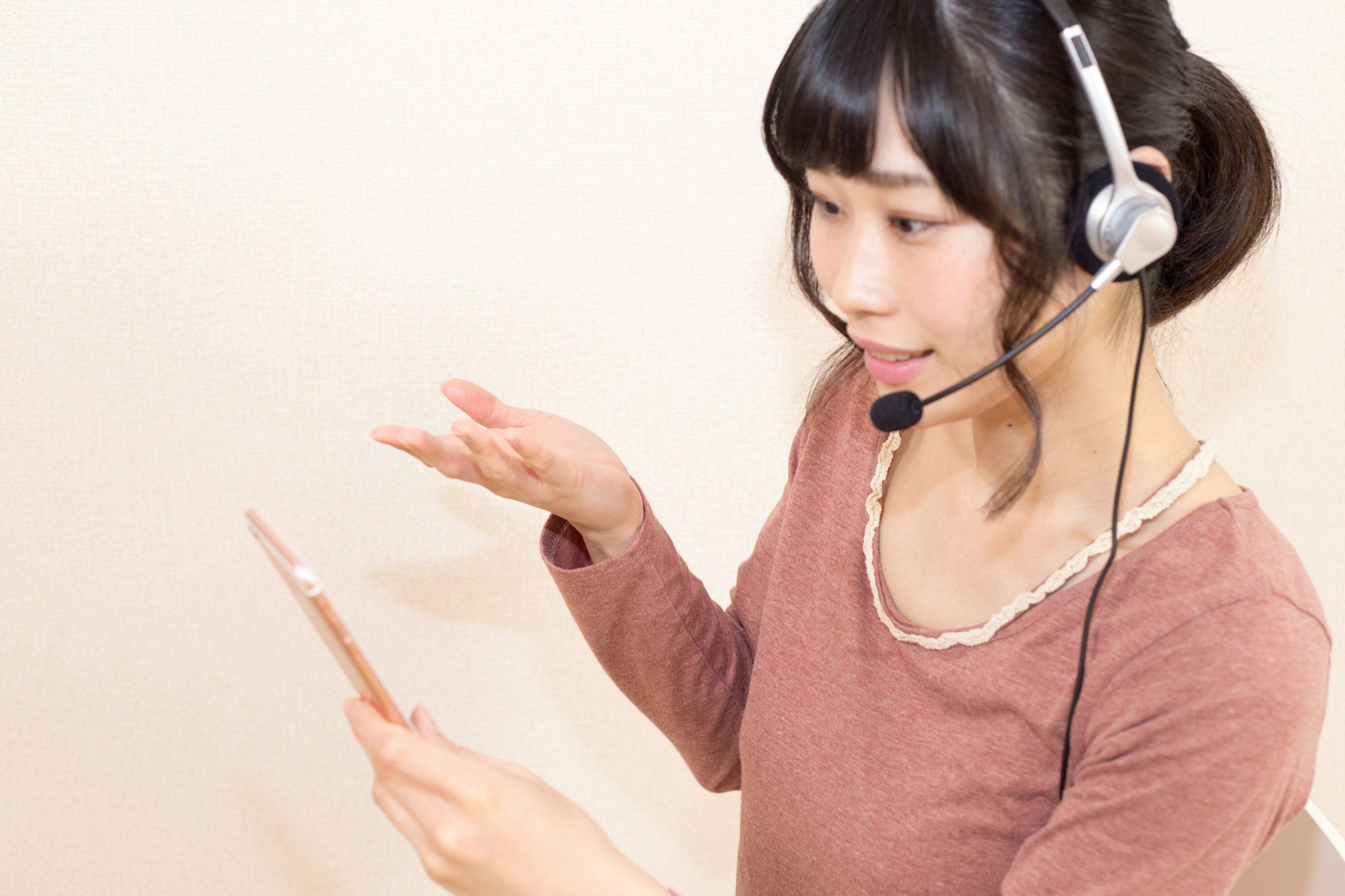 A woman wearing a headset talking while looking at a tablet