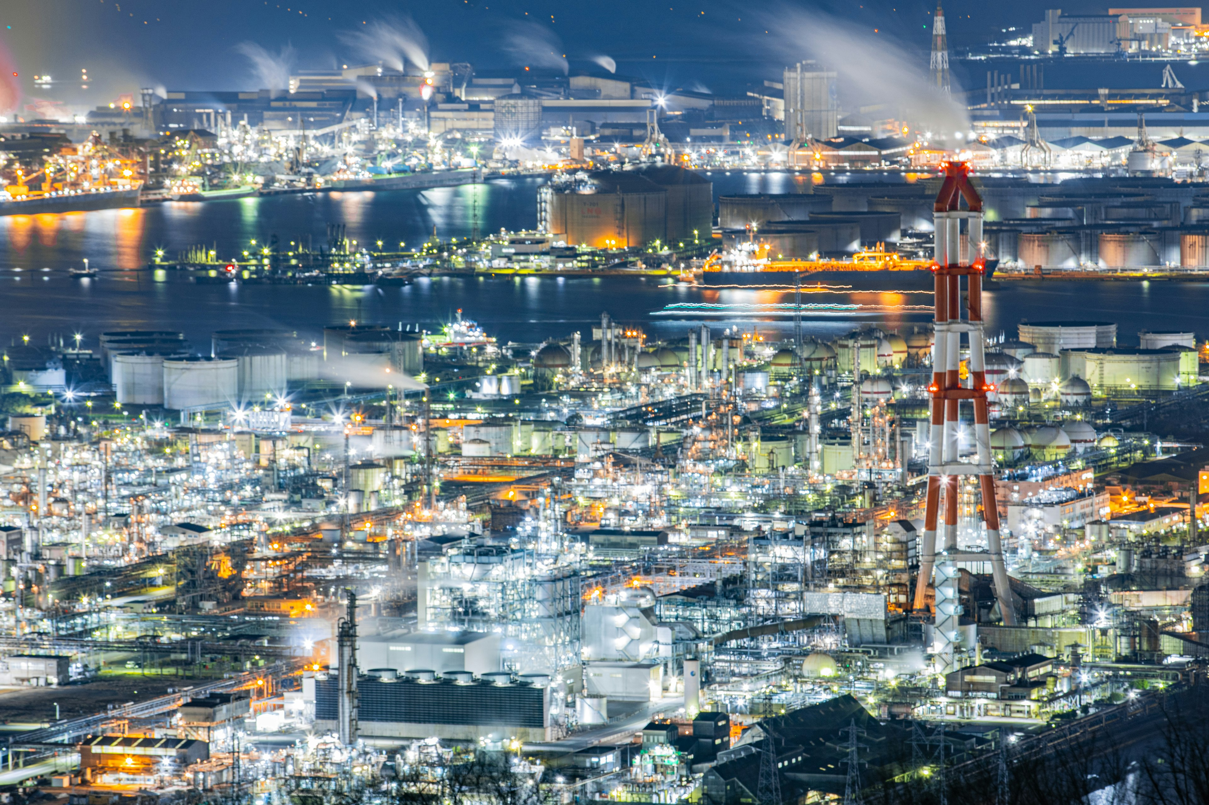 Magnifique vue nocturne d'une zone industrielle avec des usines lumineuses et des cheminées