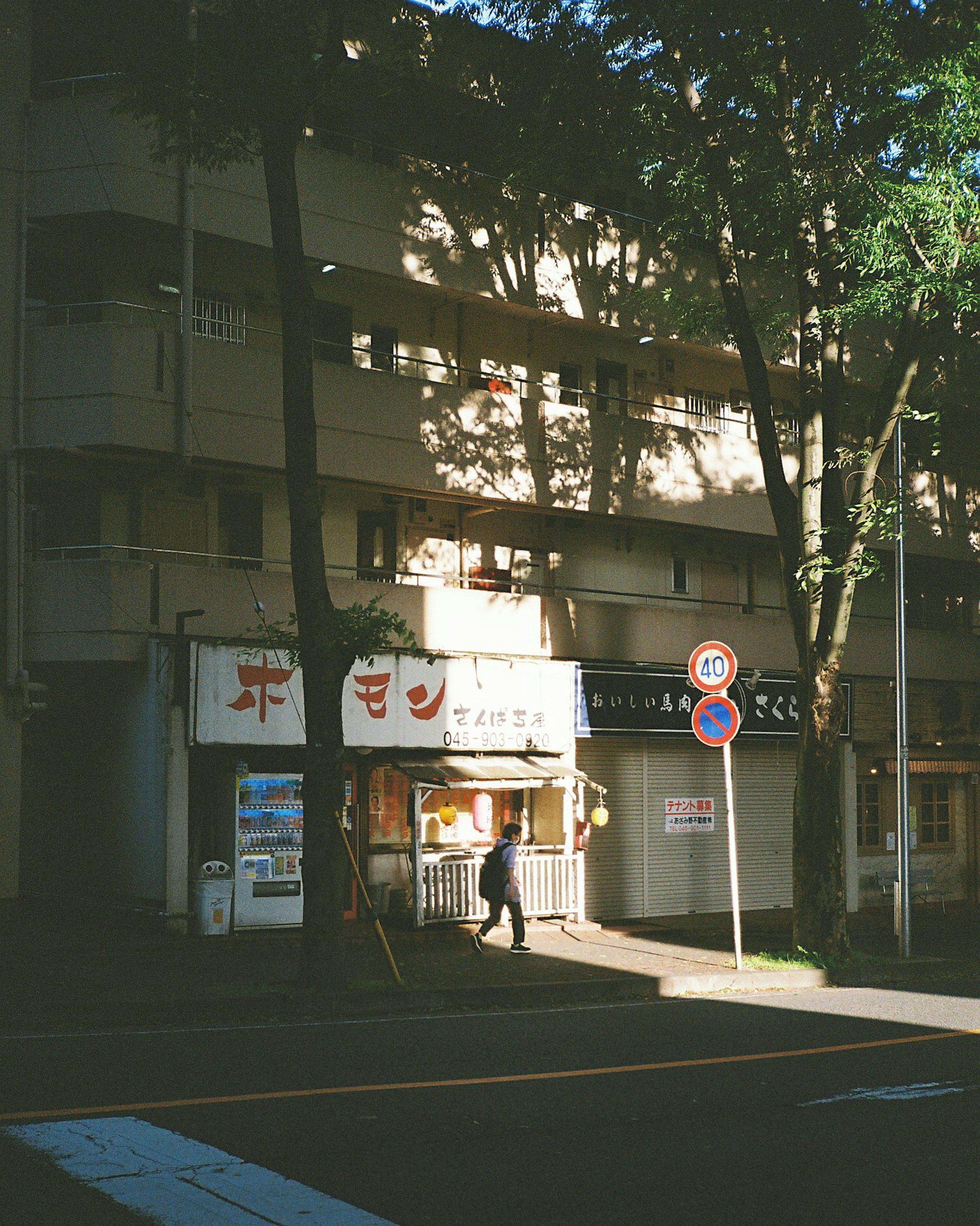 A street view featuring a small shop and an apartment building