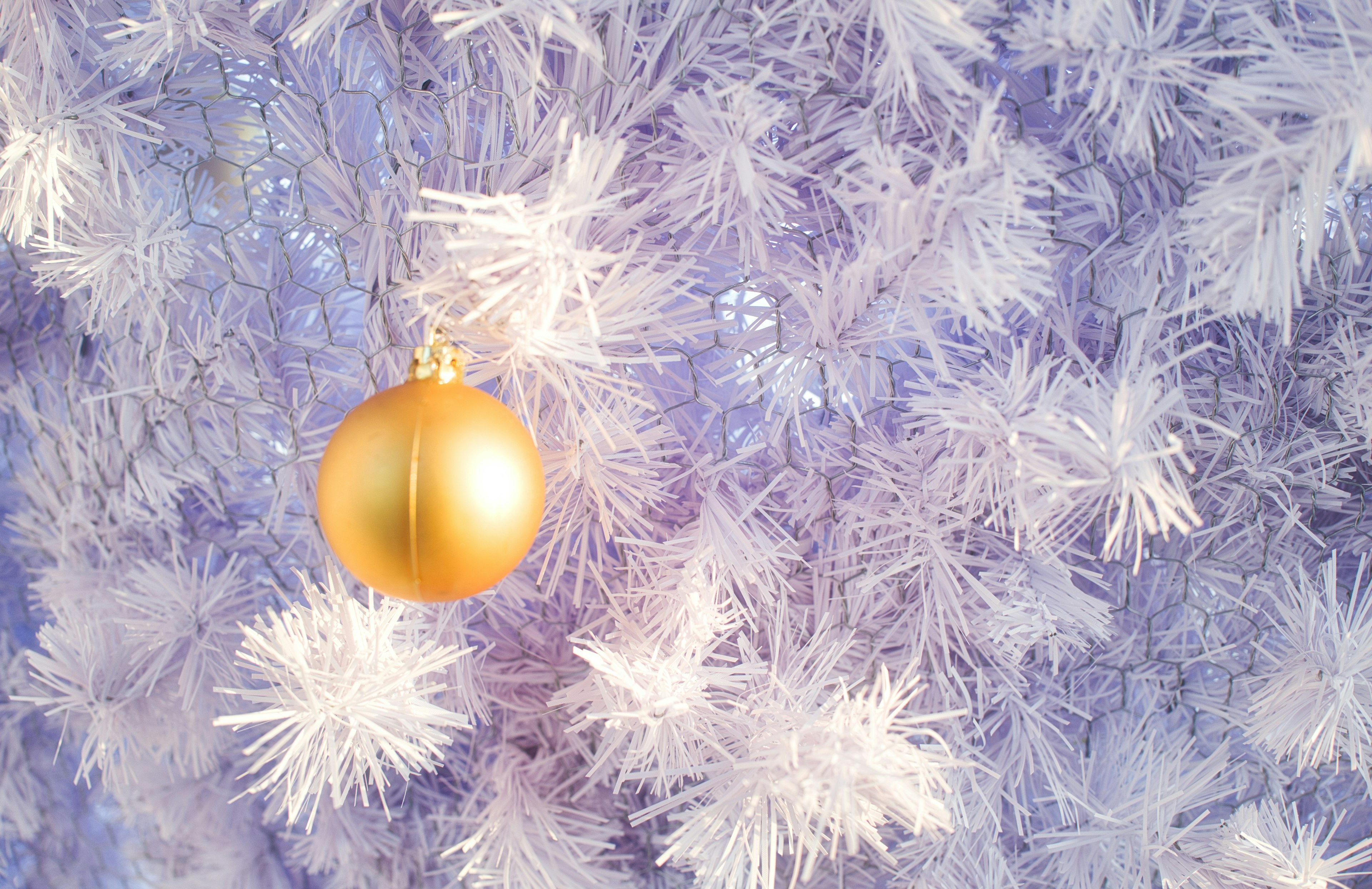 Un árbol de Navidad blanco con un adorno dorado colgante