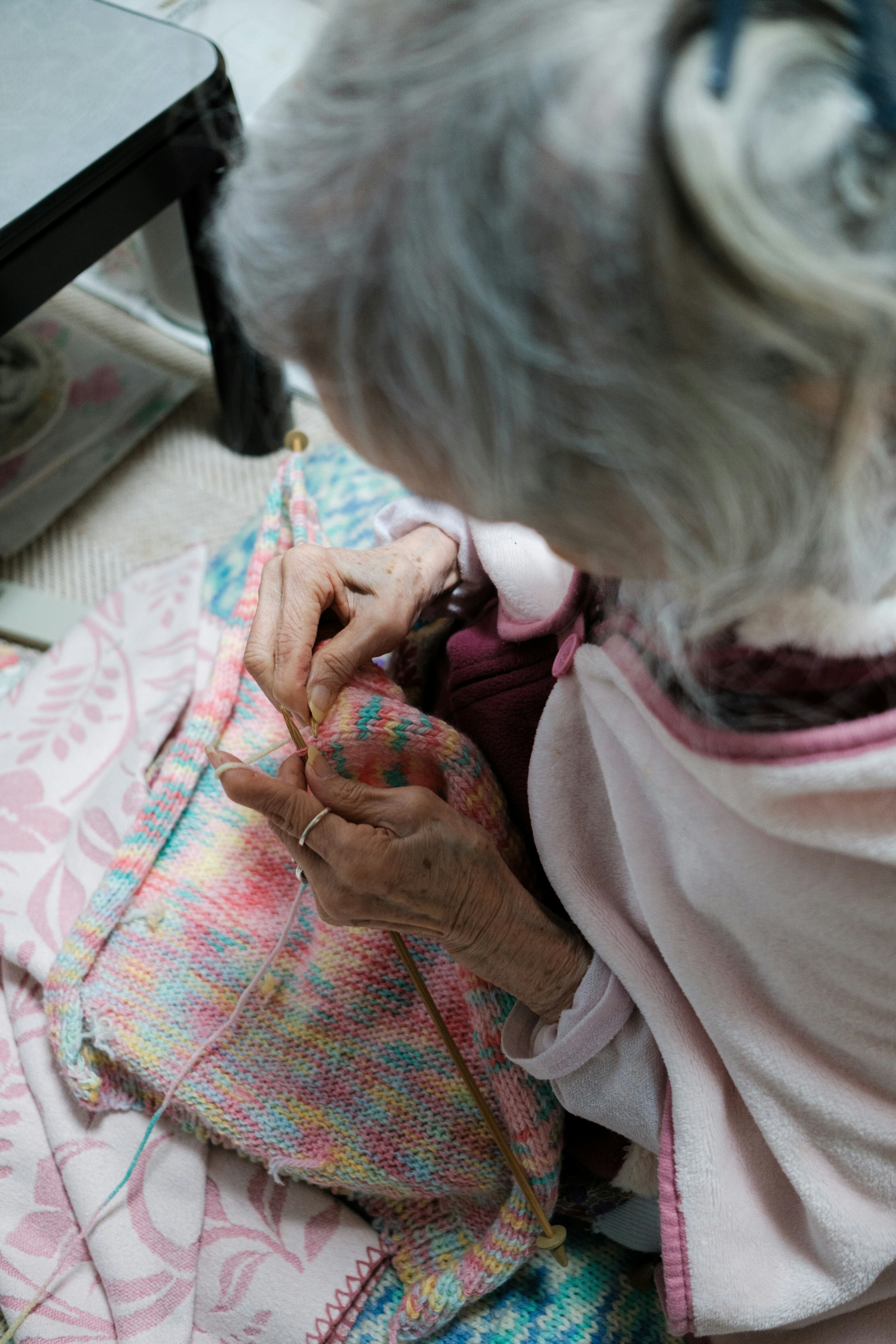 Donna anziana che lavora a maglia con un tessuto colorato