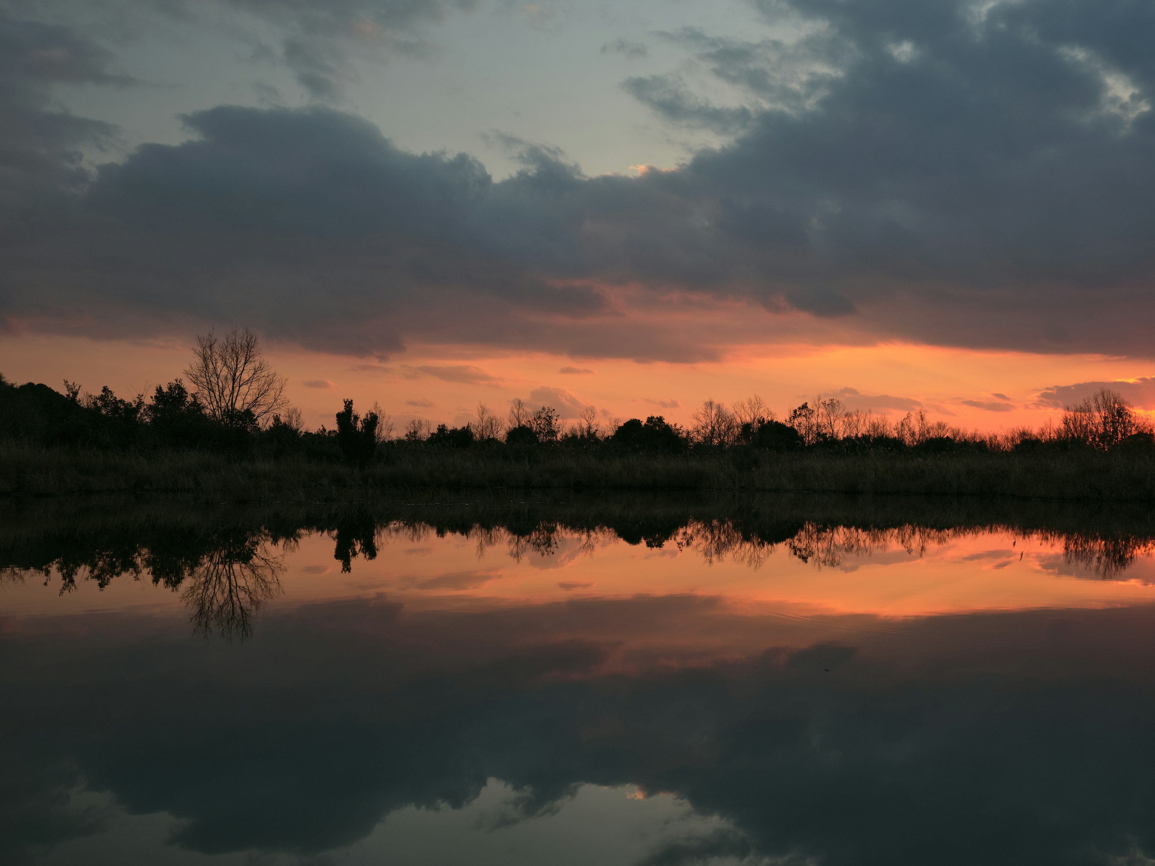 Malerscher Reflex der Sonnenuntergangswolken auf ruhigem Wasser