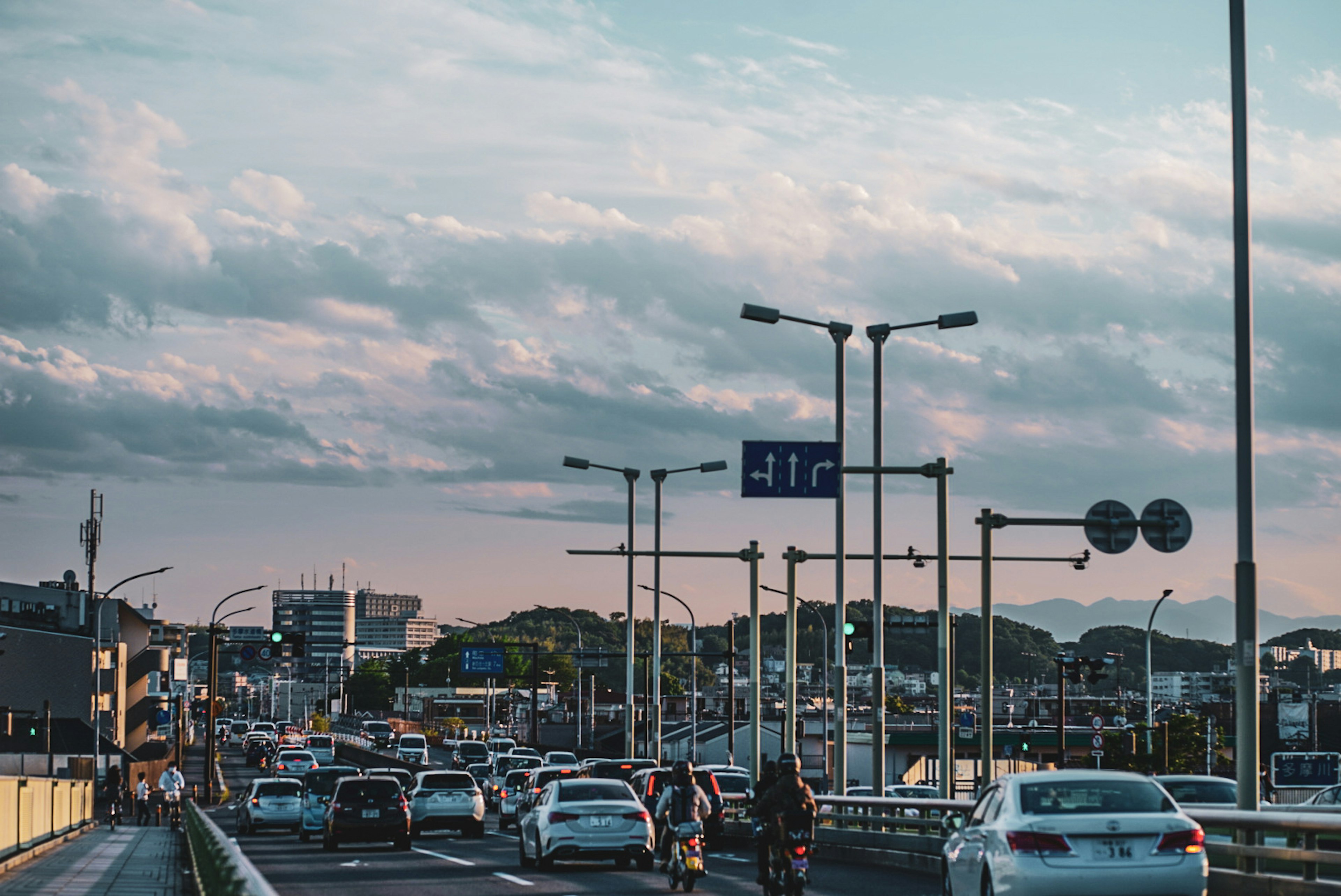 夕暮れ時の都市の交通風景 車両が多く通行する道路 空に広がる青い雲