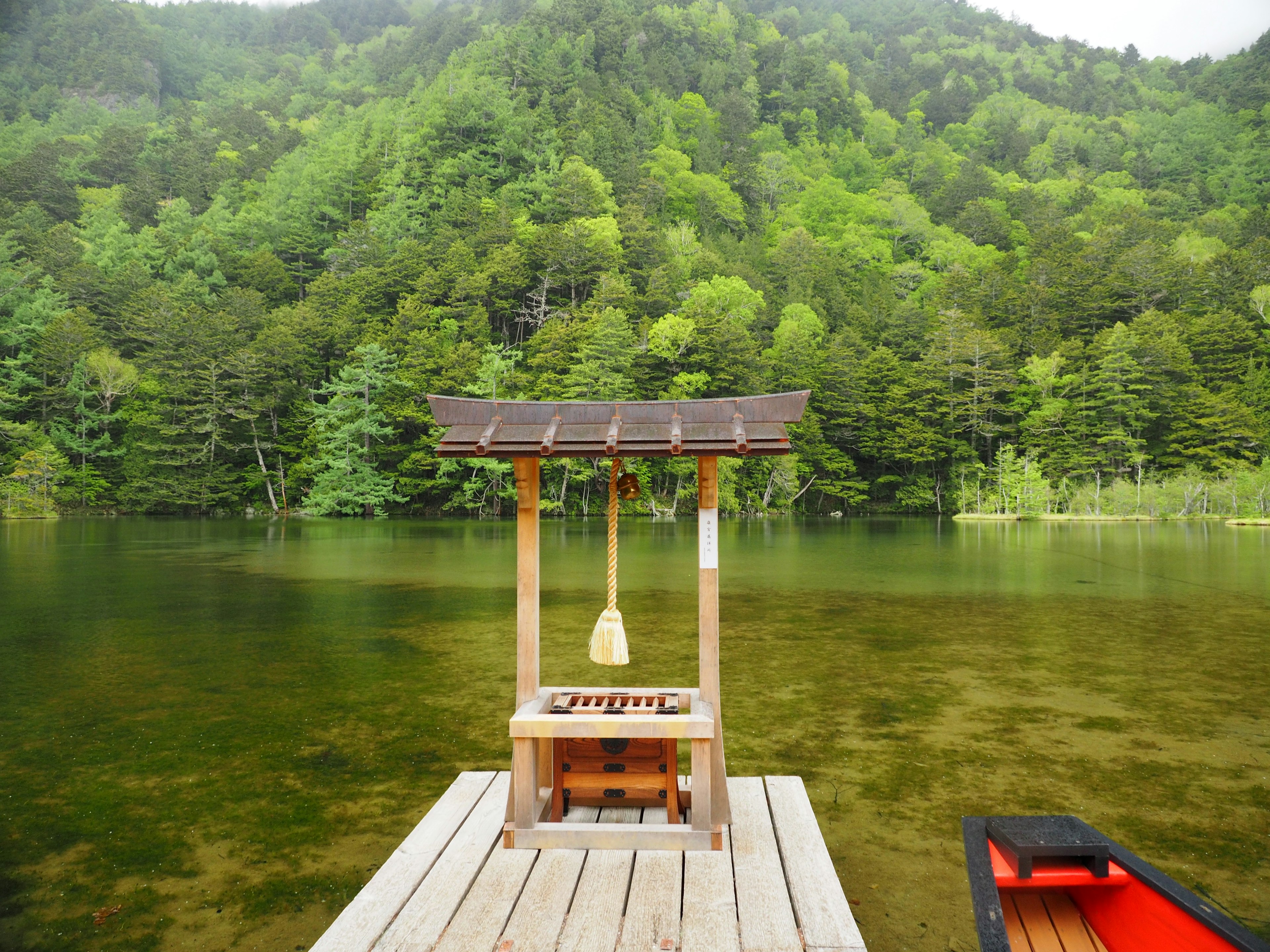 Pequeña estructura en un lago con montañas verdes al fondo