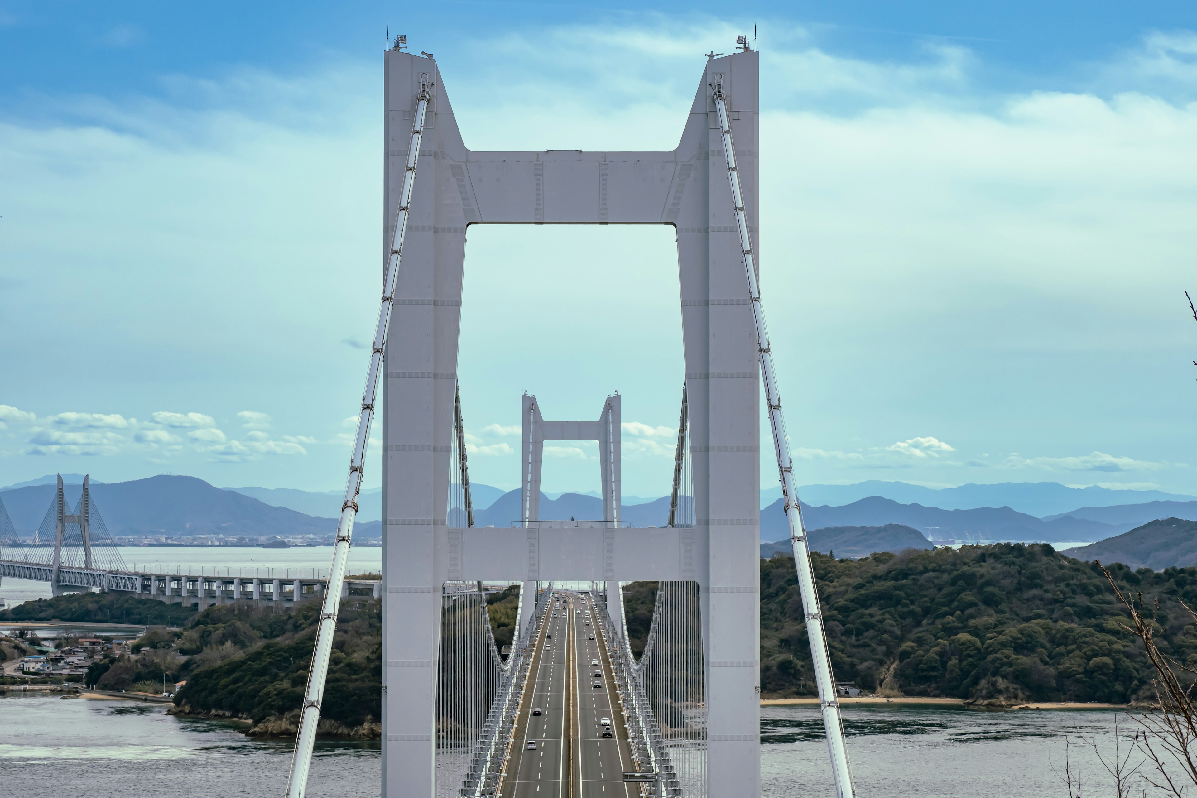 Weißer Hängebrücke mit klarem blauen Himmel Berge und Inseln im Hintergrund