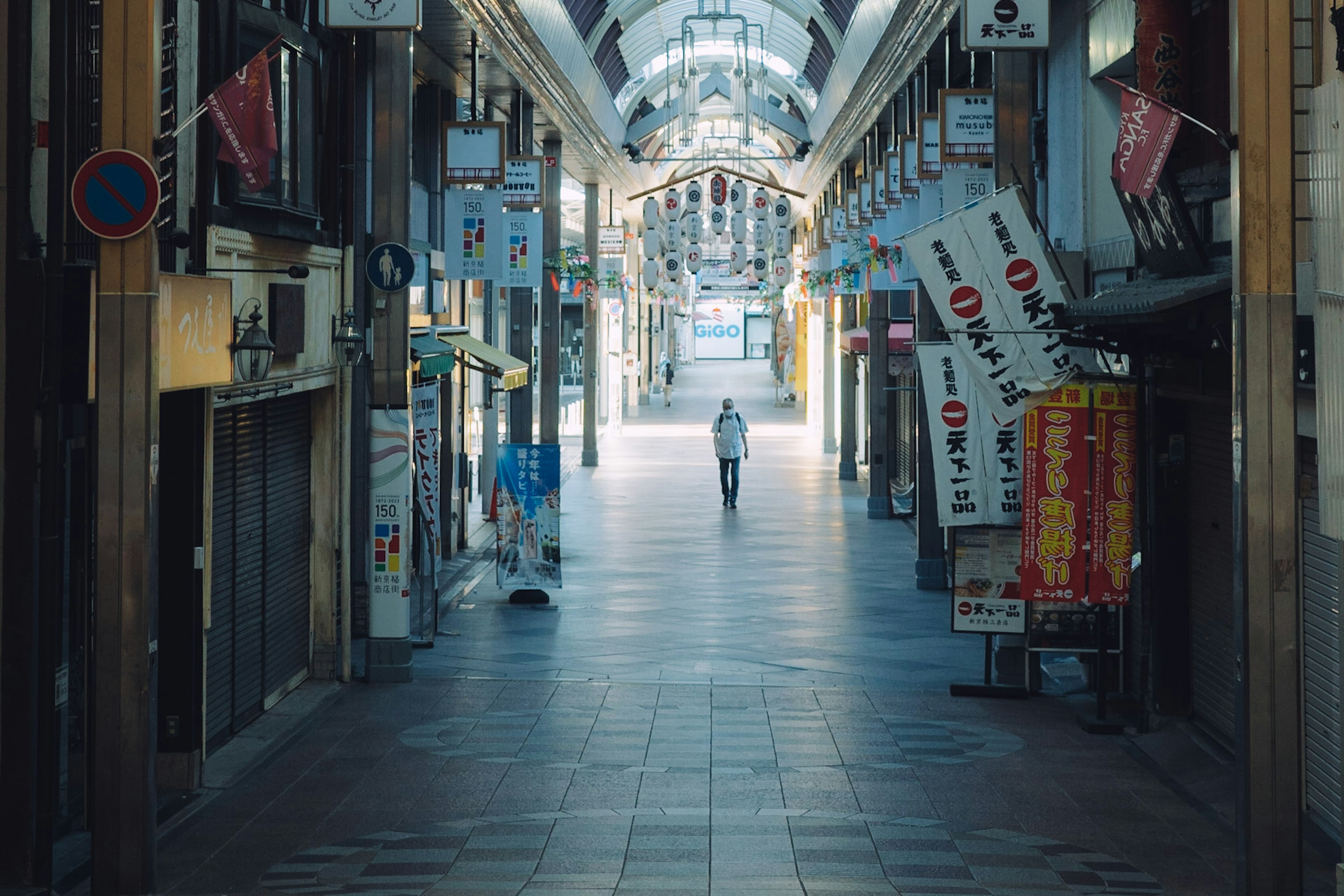 Una figura solitaria che cammina in una strada d'arcade deserta