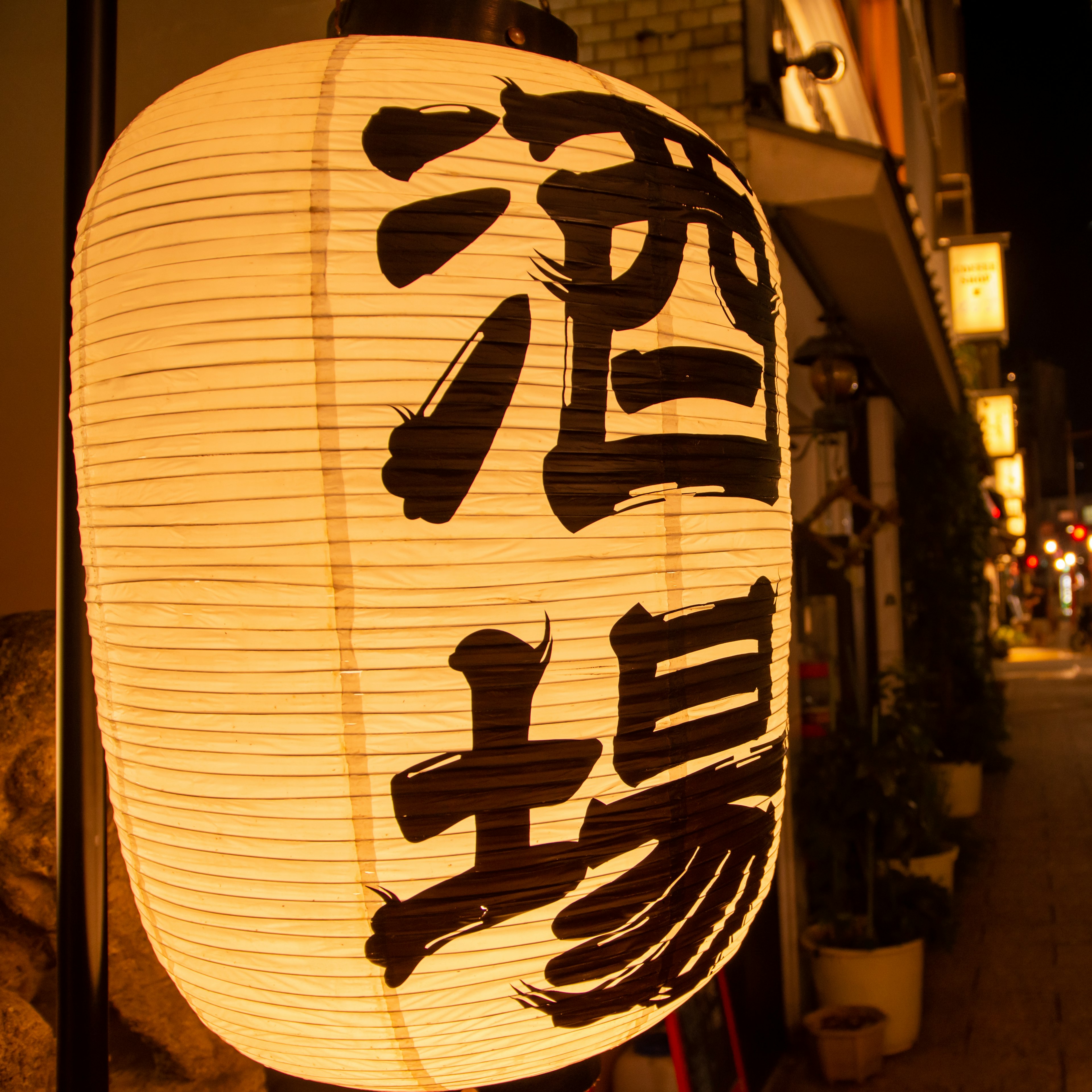 Beleuchtete Laterne mit japanischen Zeichen für eine Bar bei Nacht