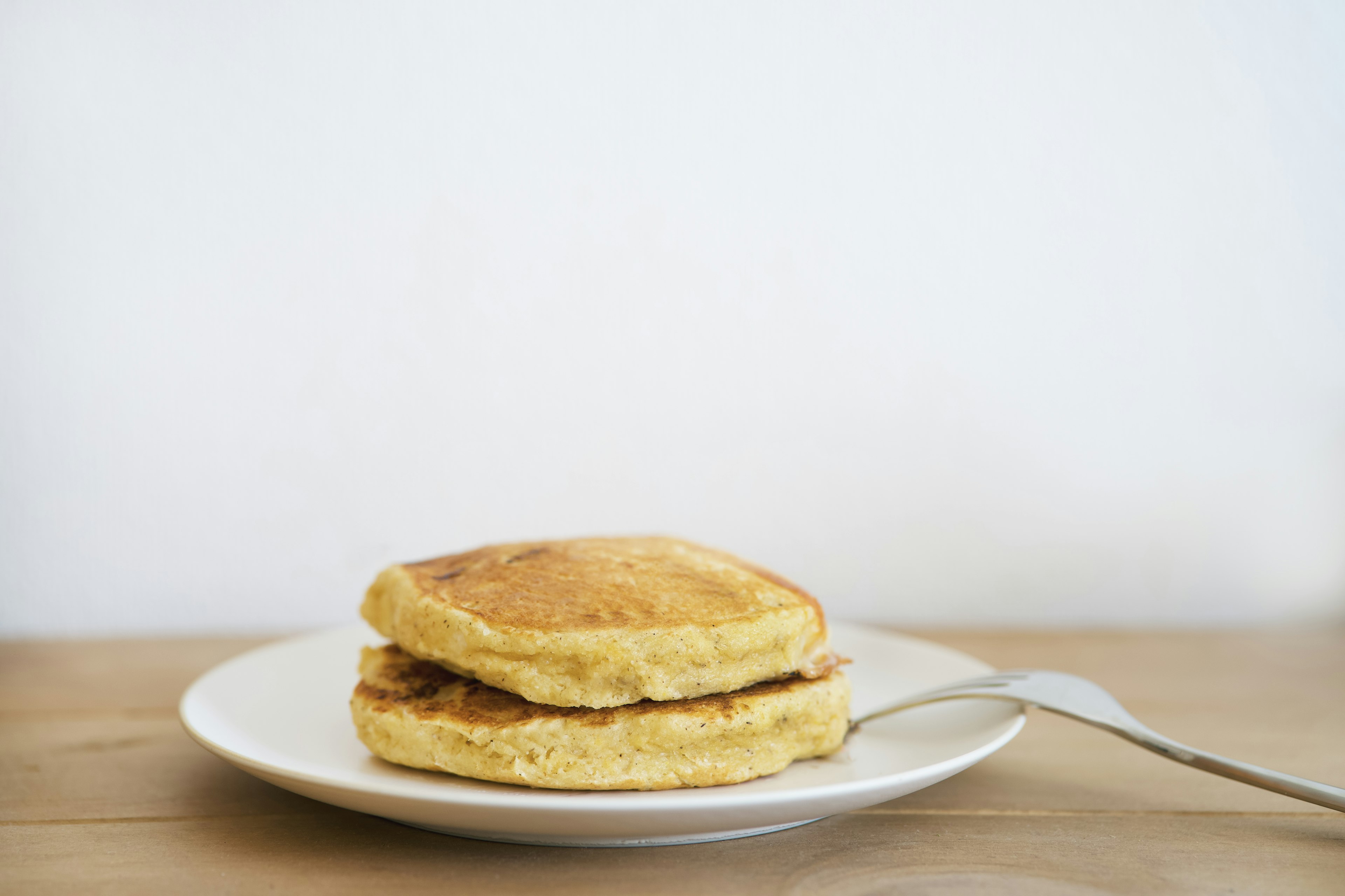 Montón de pancakes esponjosos en un plato blanco contra un fondo blanco