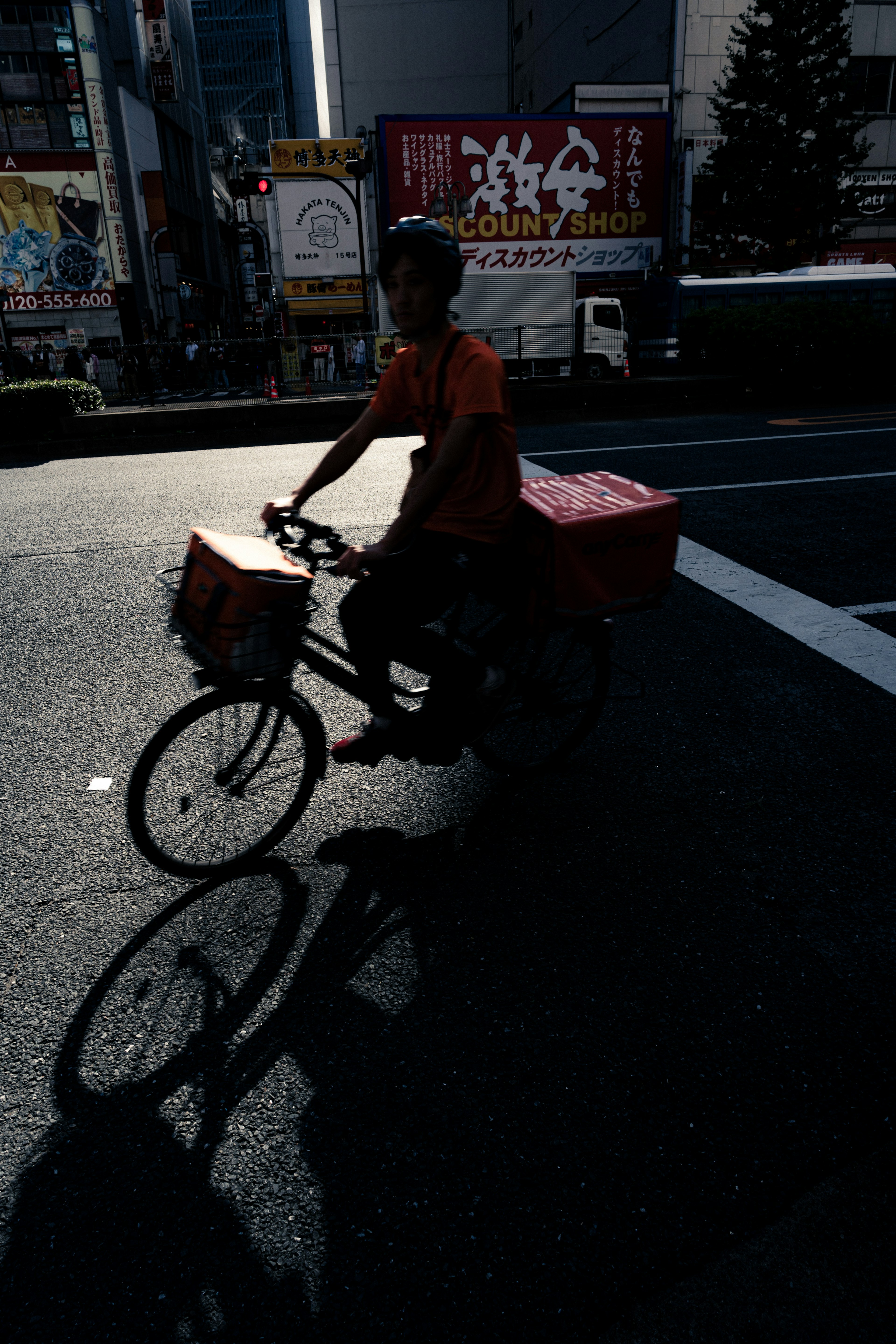 Silhouette of a delivery person riding a bicycle in a city street