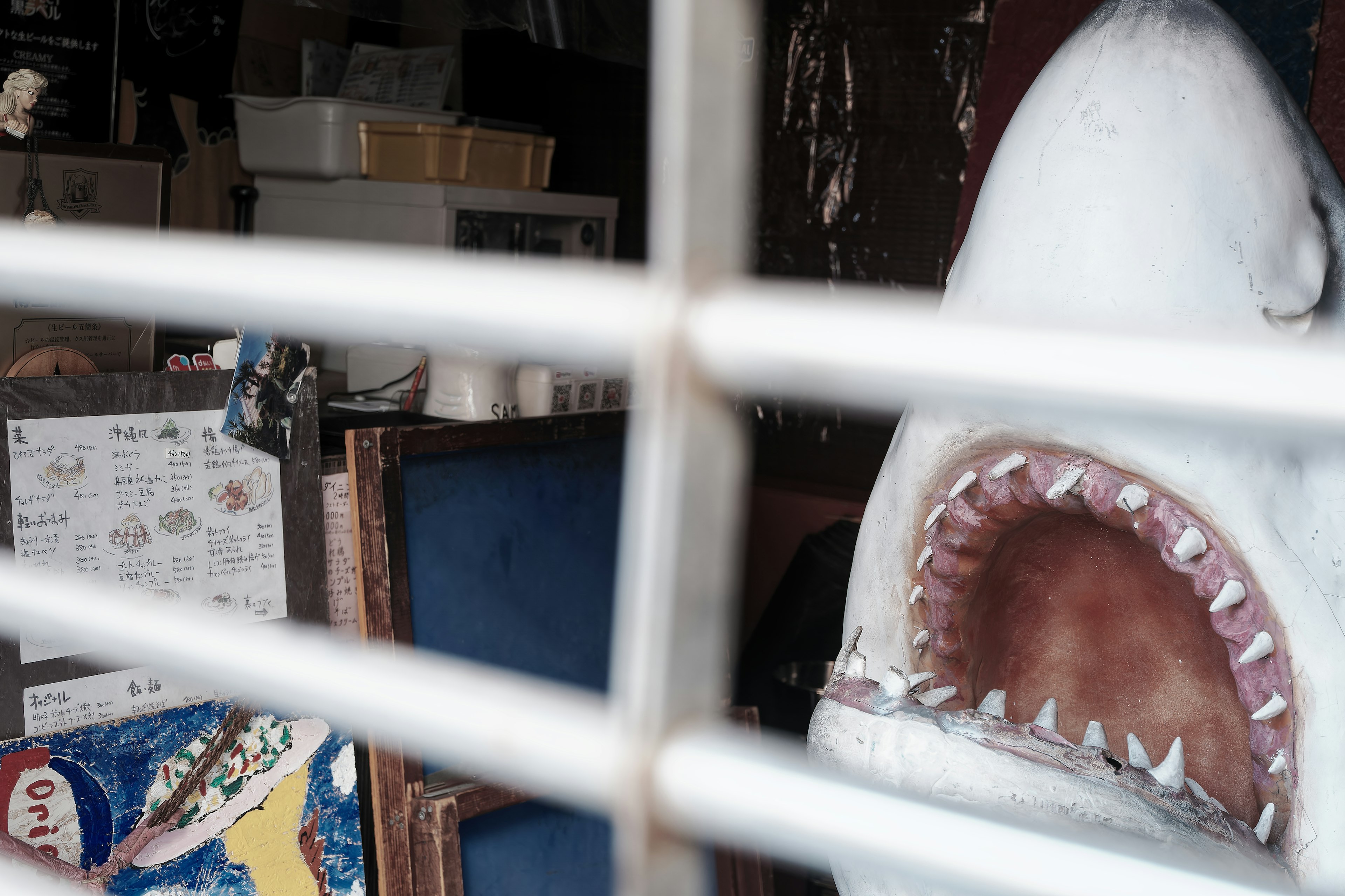 A shark sculpture visible through bars in a store interior