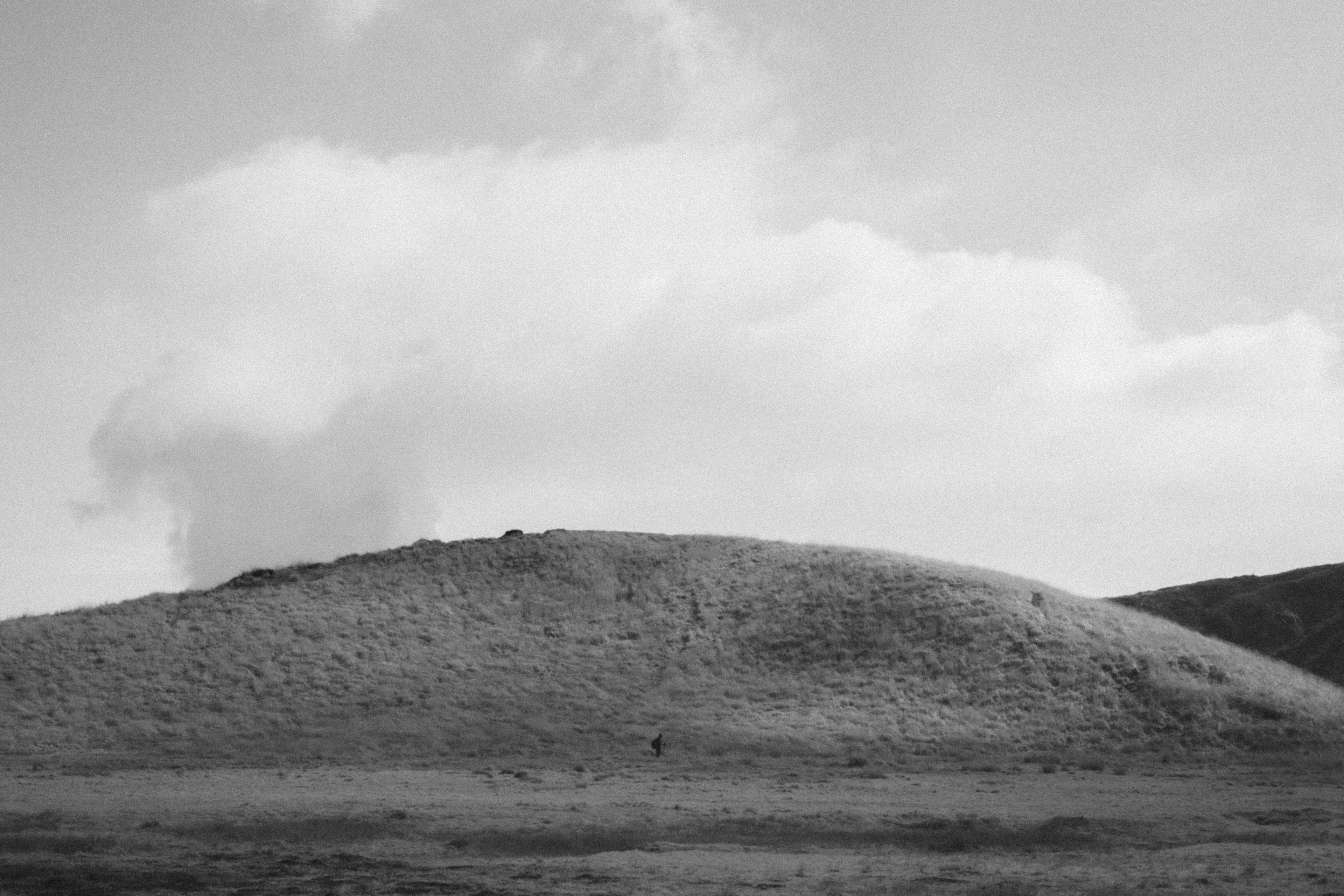 Schwarz-weiß Landschaft mit einem Hügel und Wolken