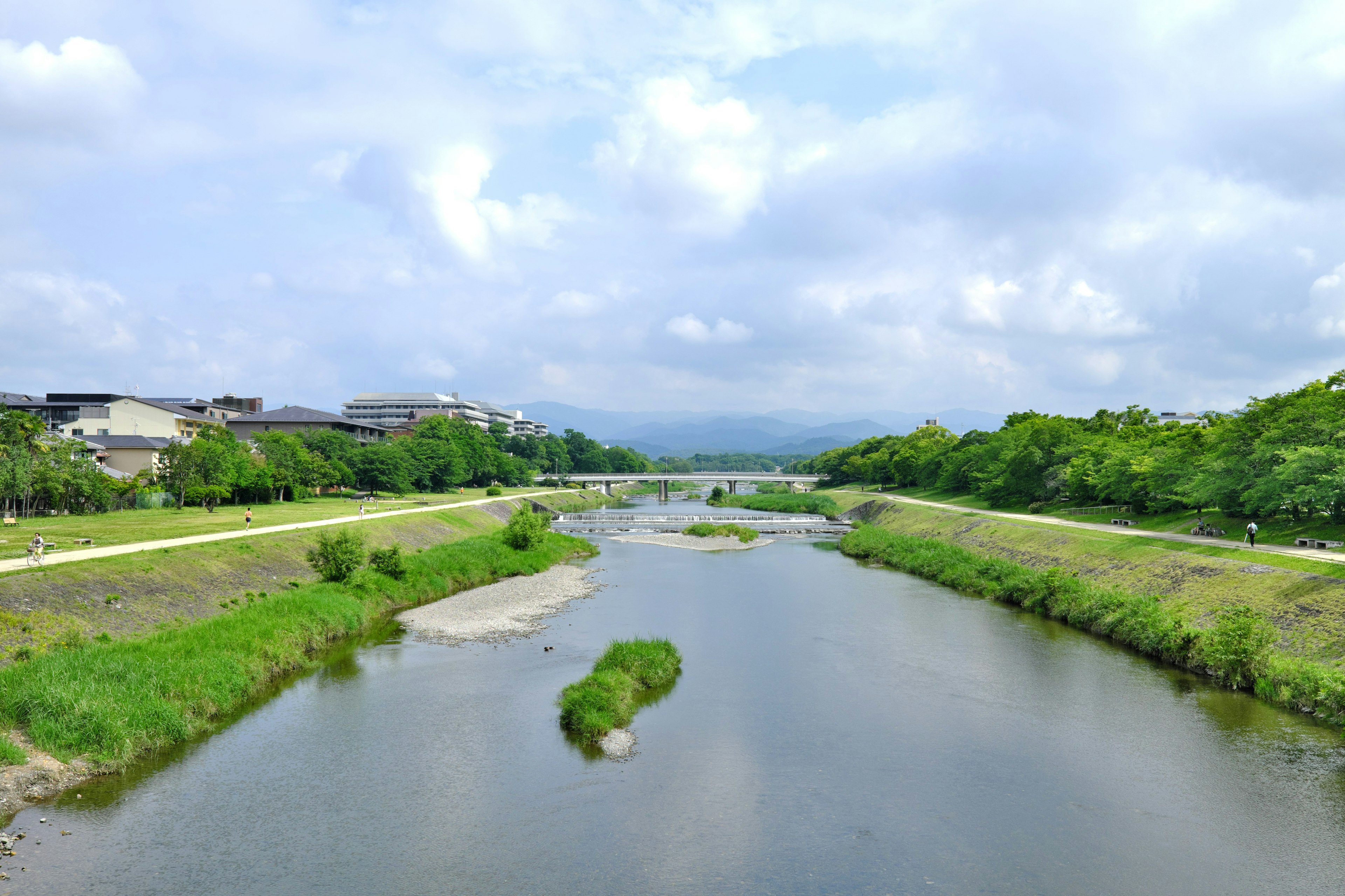 Malersicher Blick auf einen Fluss umgeben von Grün und einem bewölkten Himmel