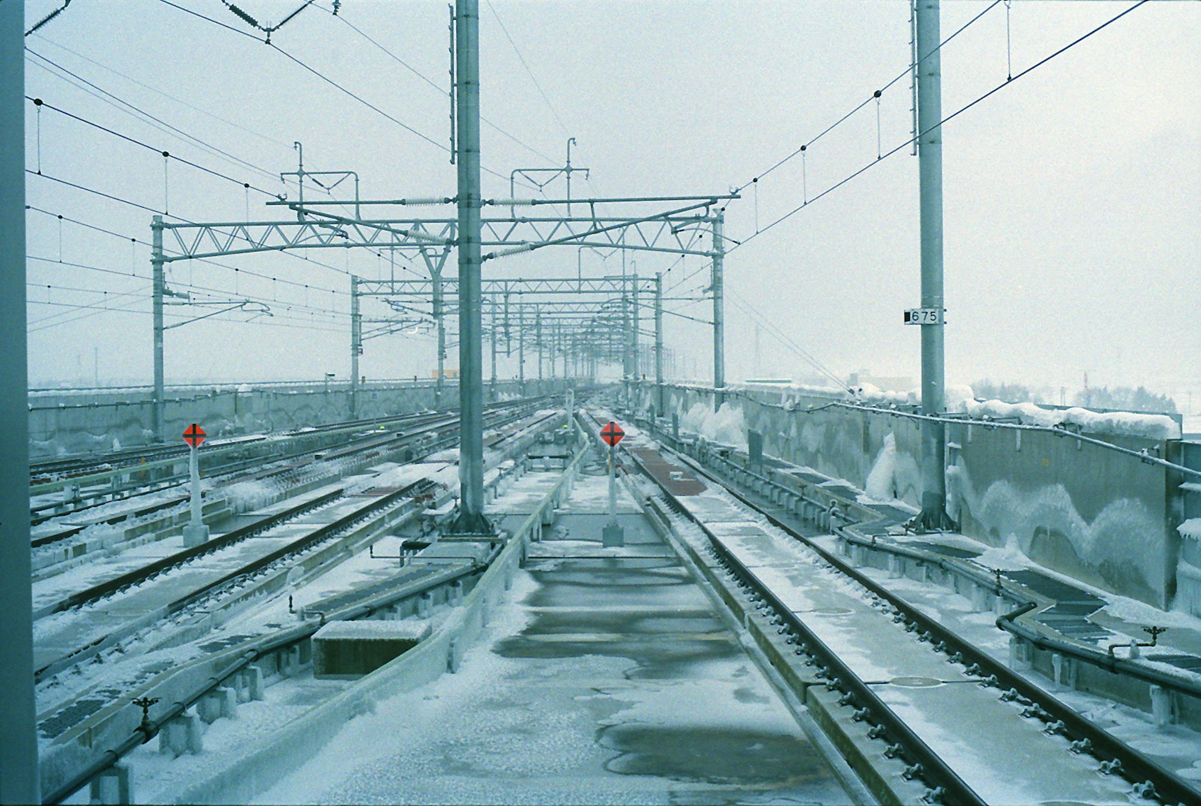 Vías de tren cubiertas de nieve y líneas aéreas en un paisaje invernal