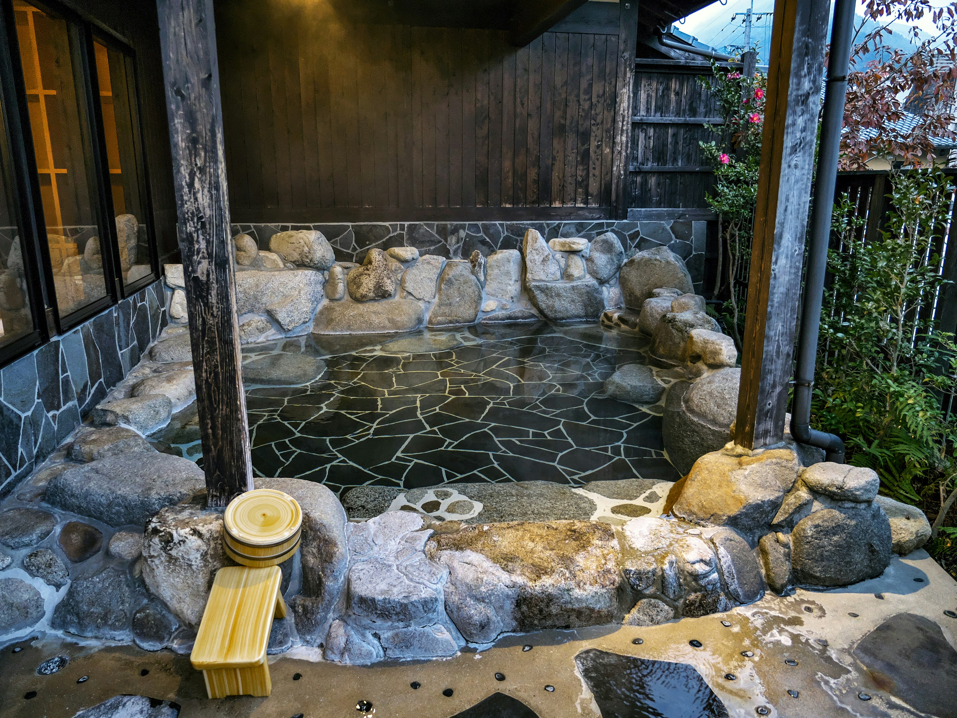 Scenic view of a natural stone hot spring bath surrounded by wooden structure