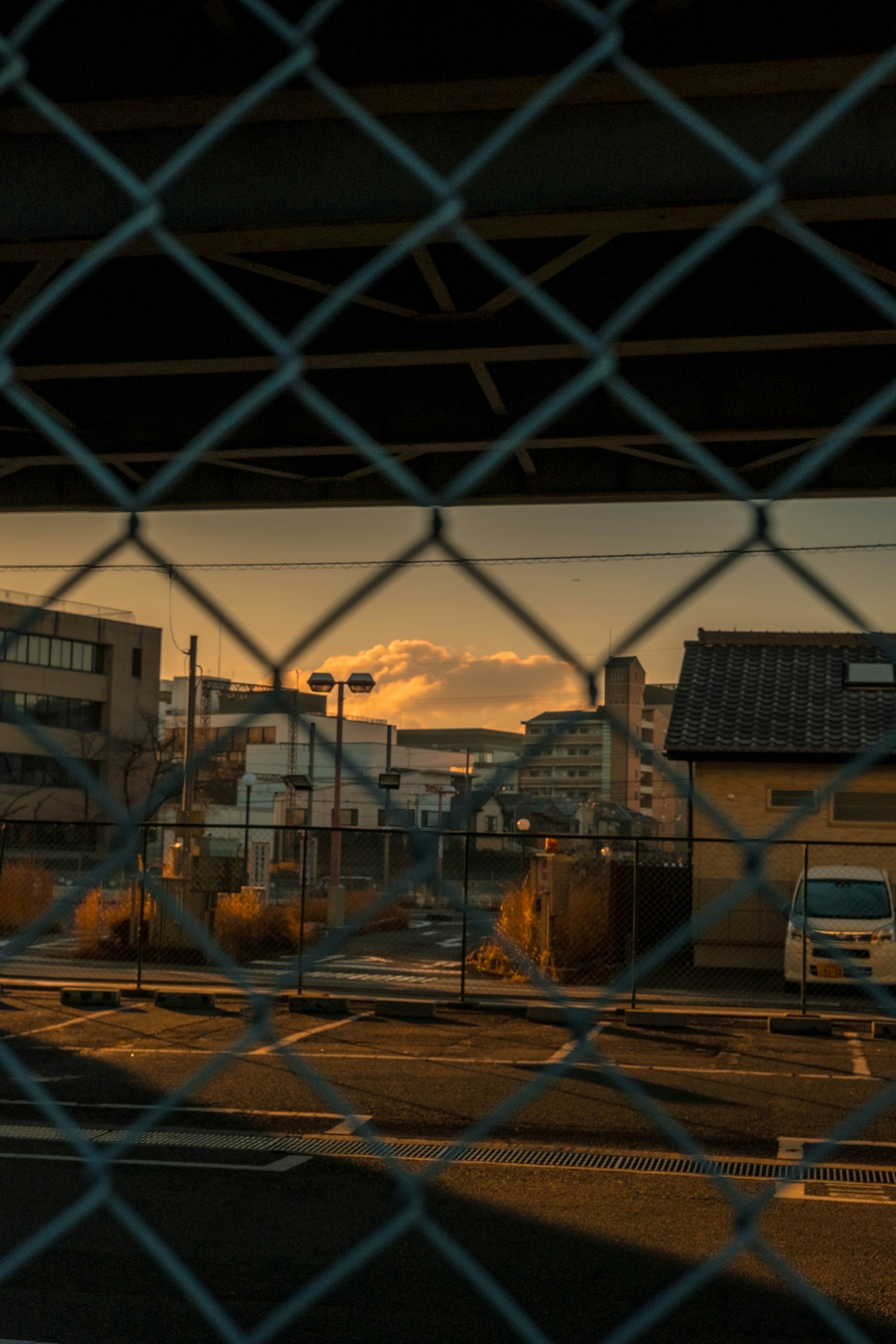 Paesaggio urbano con tramonto dorato visto attraverso una recinzione a catena