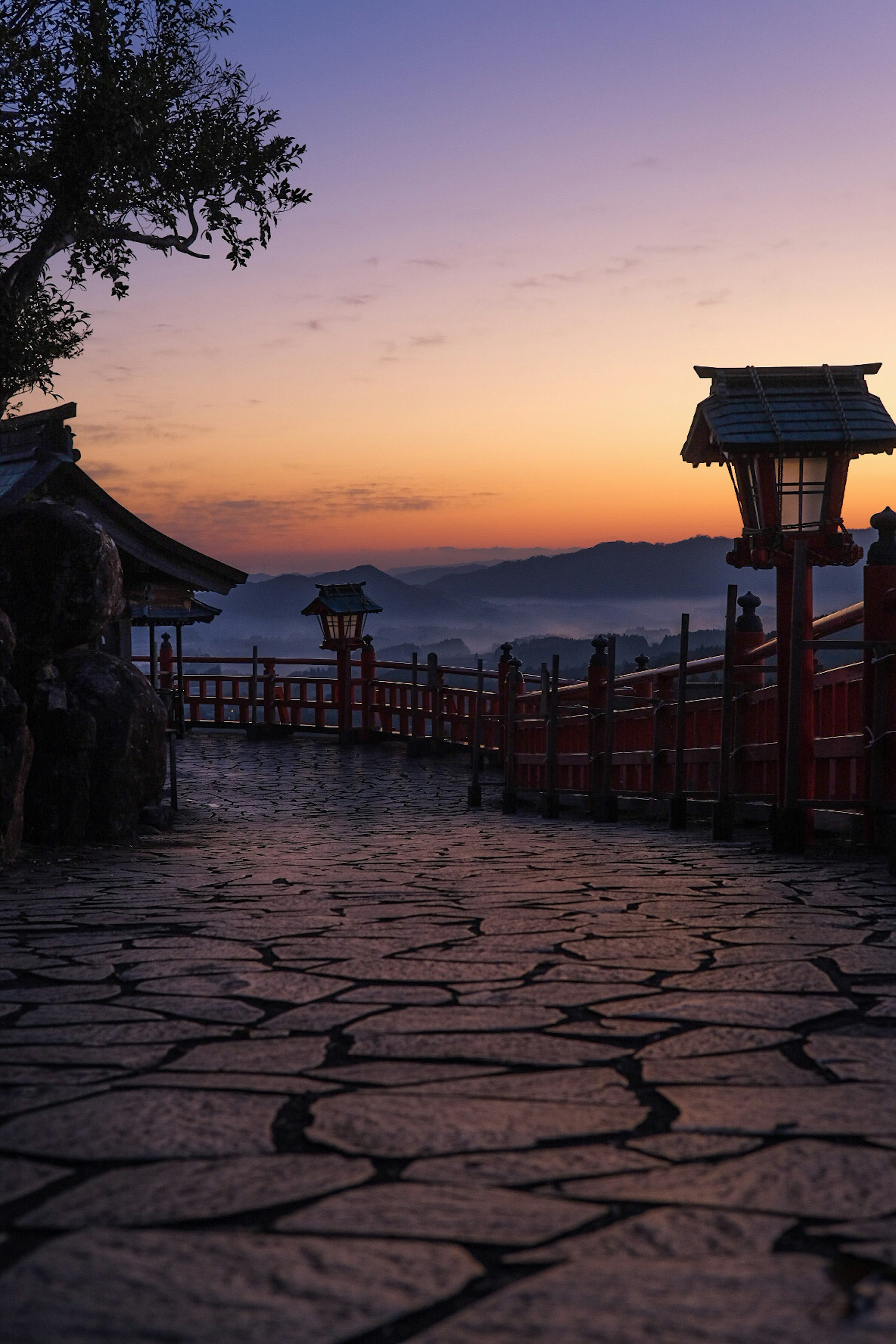 Vue pittoresque d'un chemin en pierre et d'un pont à balustrade rouge au coucher du soleil