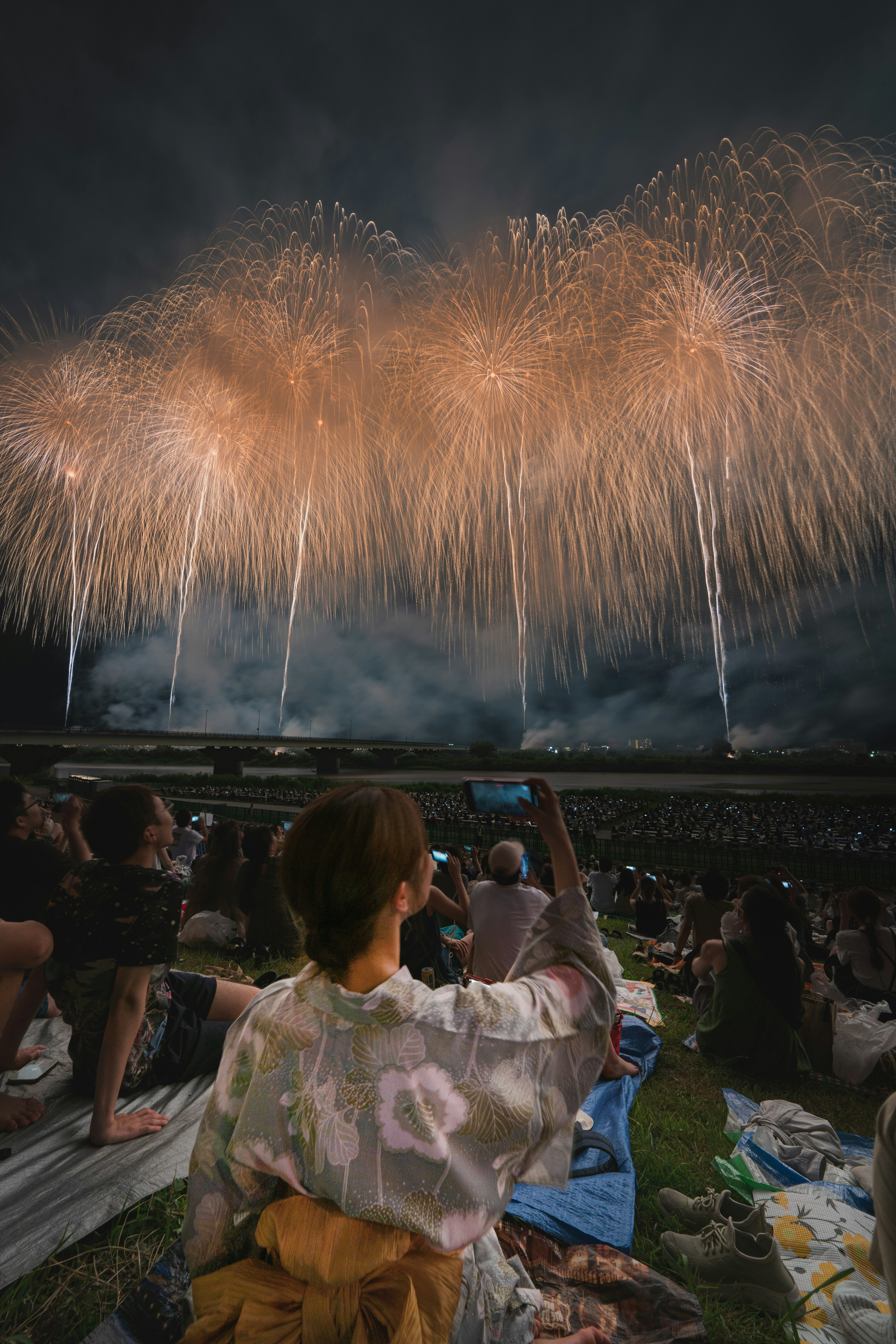 Una donna in yukata che guarda i fuochi d'artificio nel cielo notturno