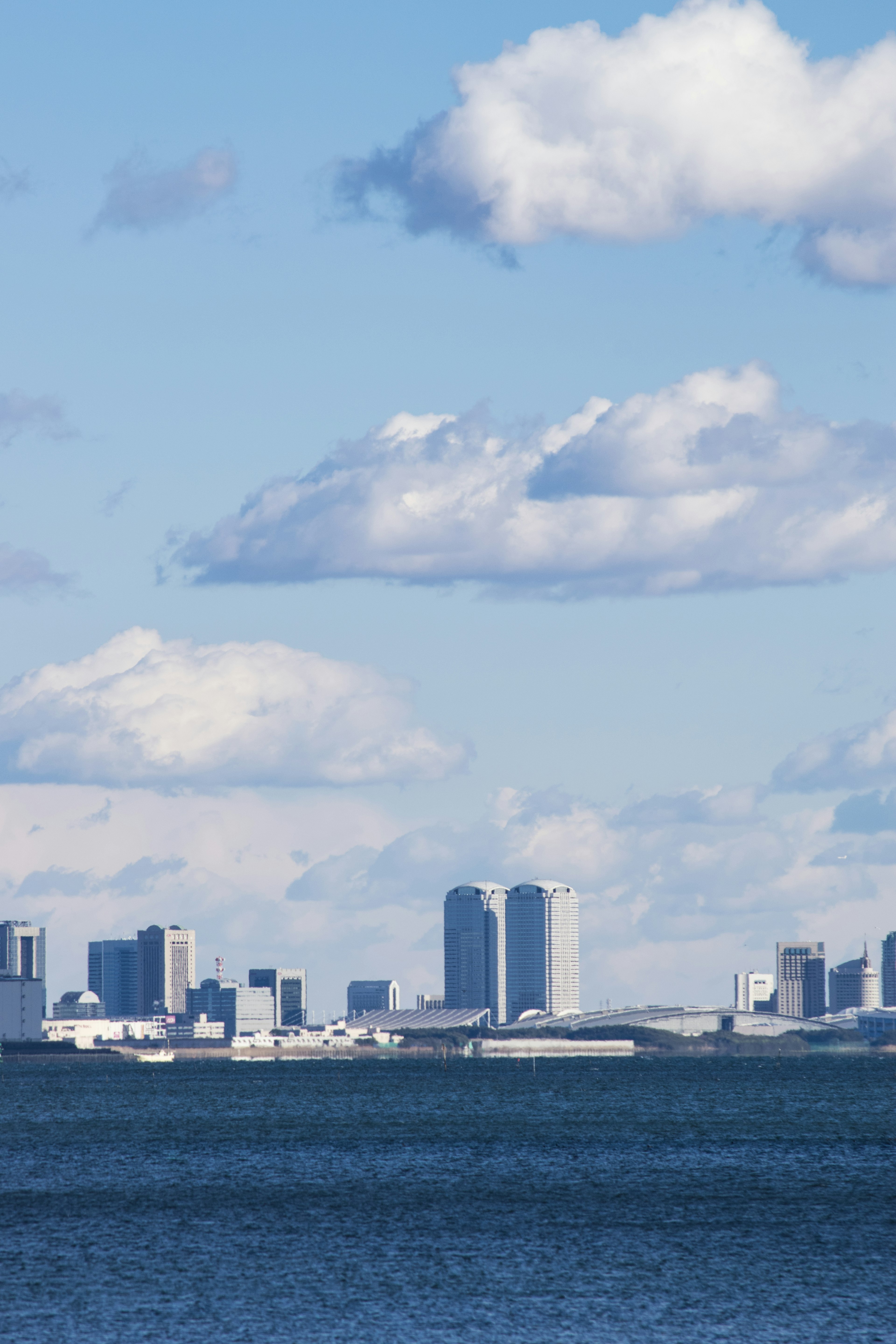 Stadtansicht mit blauem Himmel und weißen Wolken über Wasser