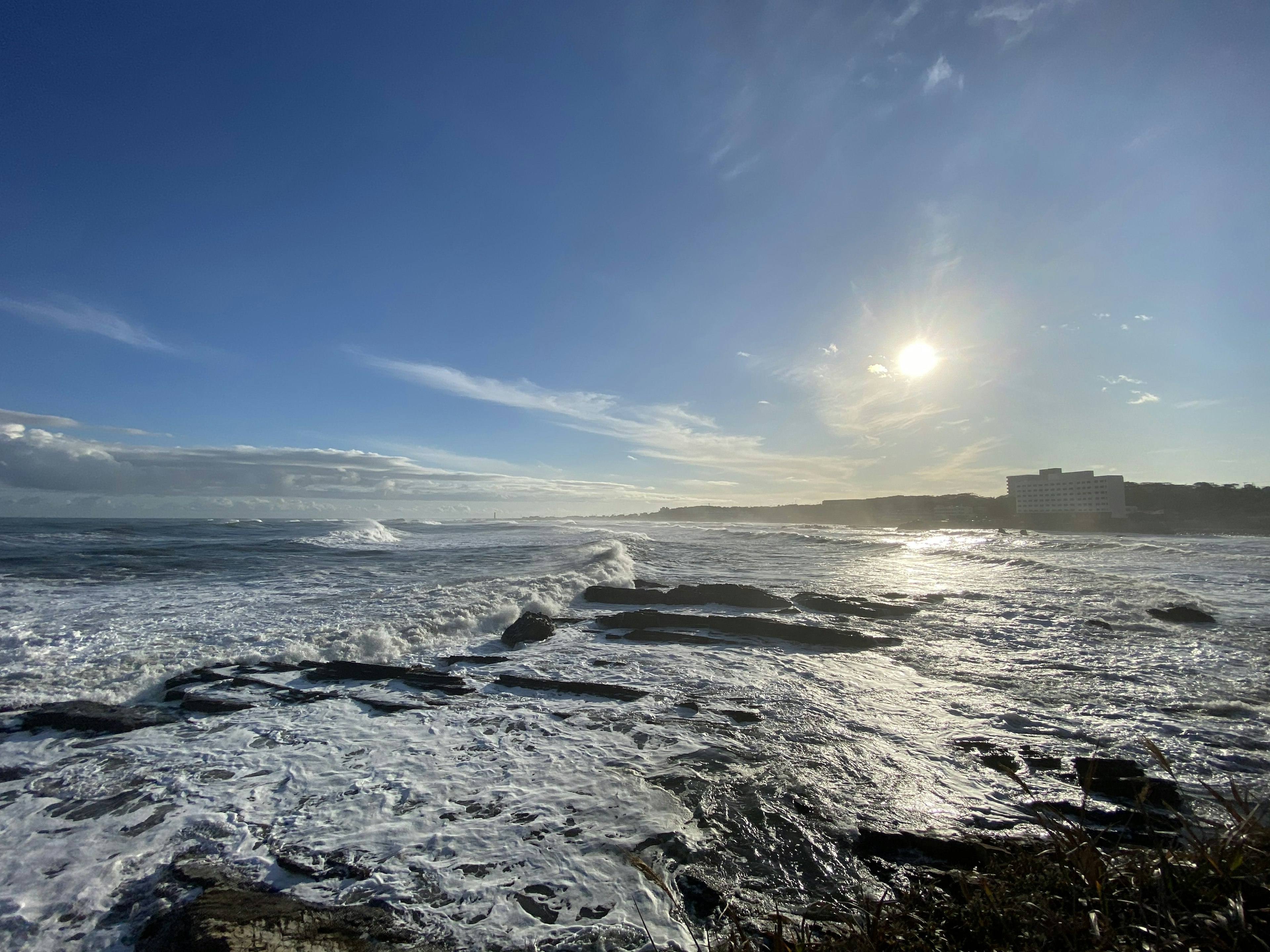 Scène côtière avec ciel bleu et nuages vagues s'écrasant sur des rochers