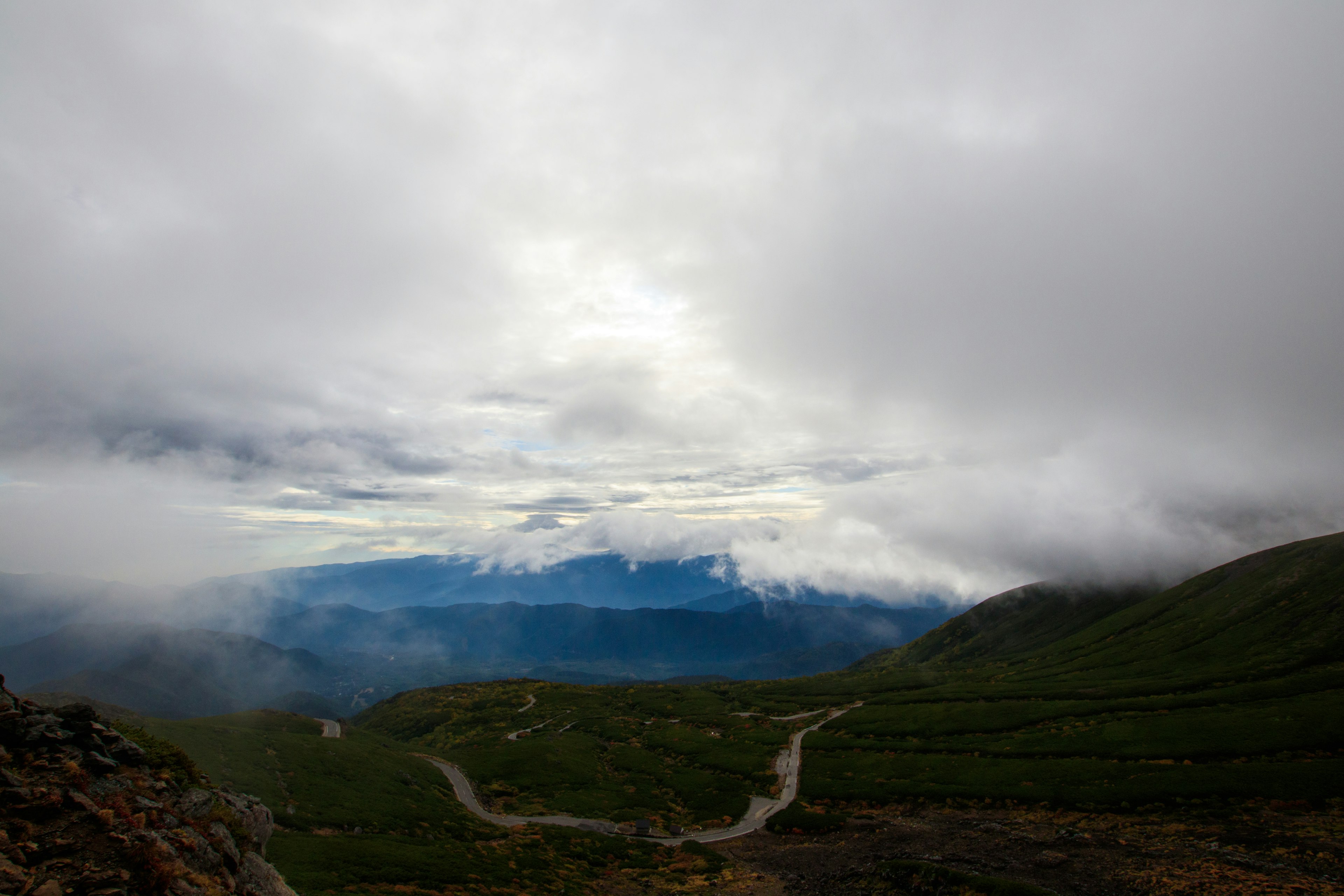 Landschaft von Bergen unter bewölktem Himmel mit kurvenreicher Straße