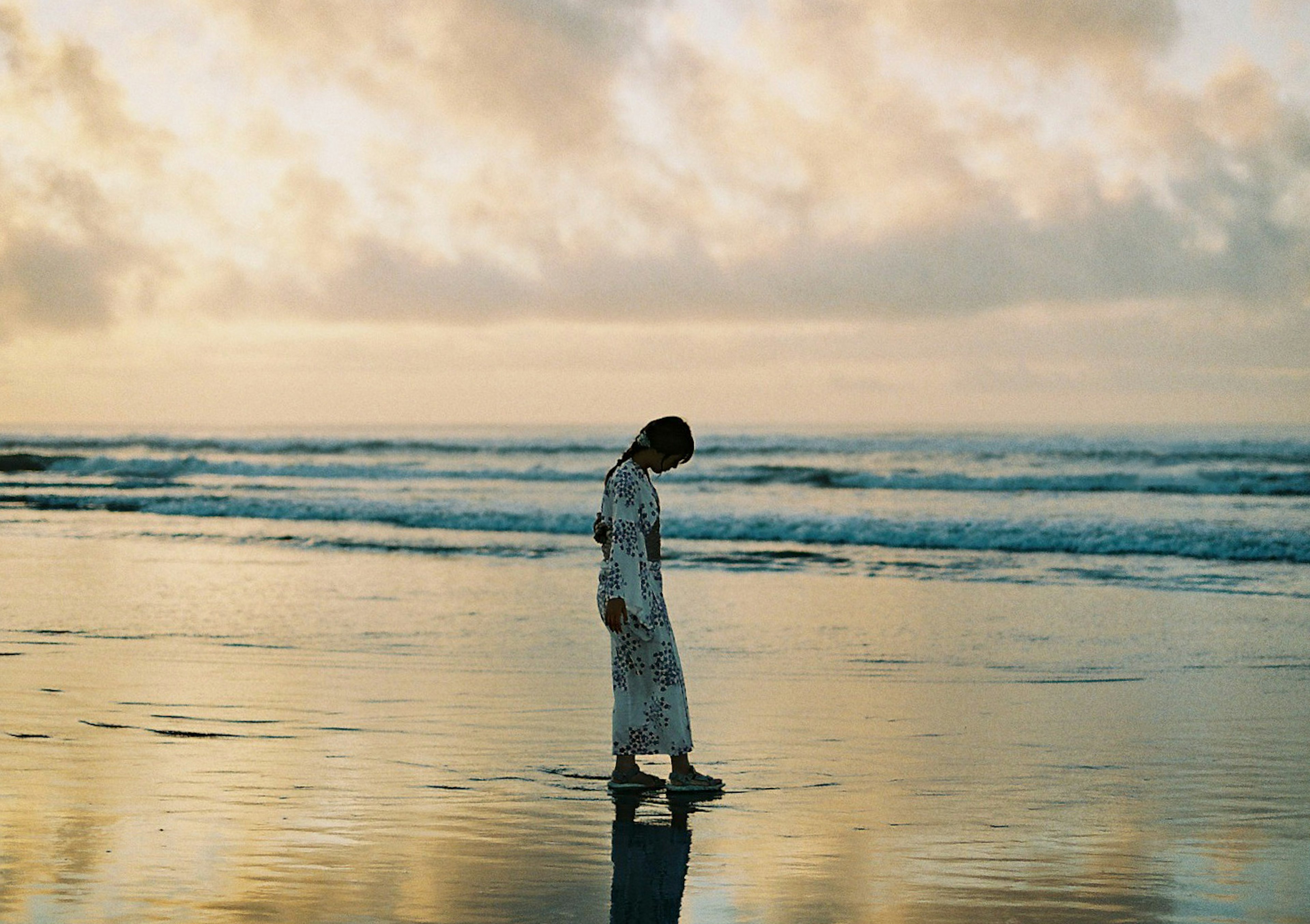 海岸で白い服を着た女性が歩いている夕暮れの風景