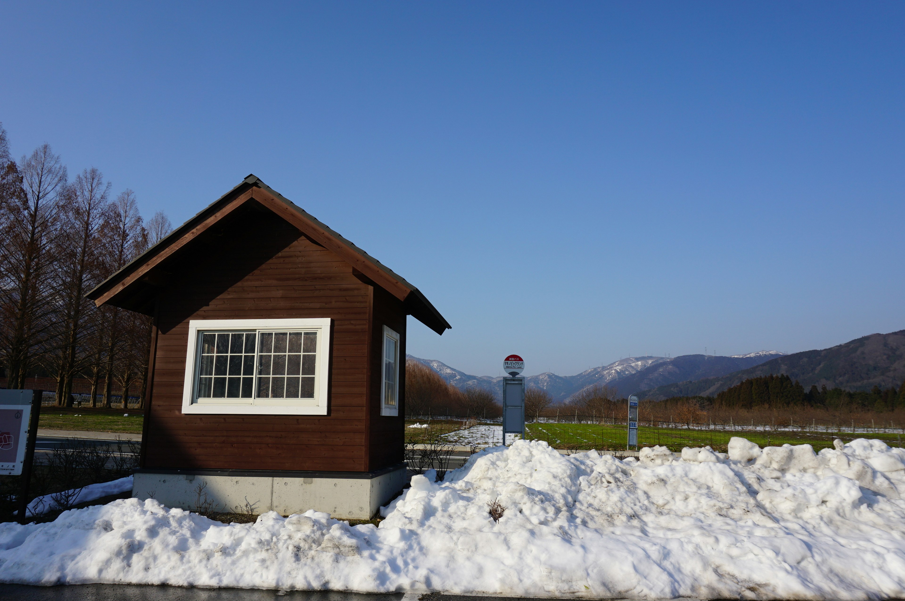 Piccola cabina marrone in un paesaggio innevato sotto un cielo azzurro