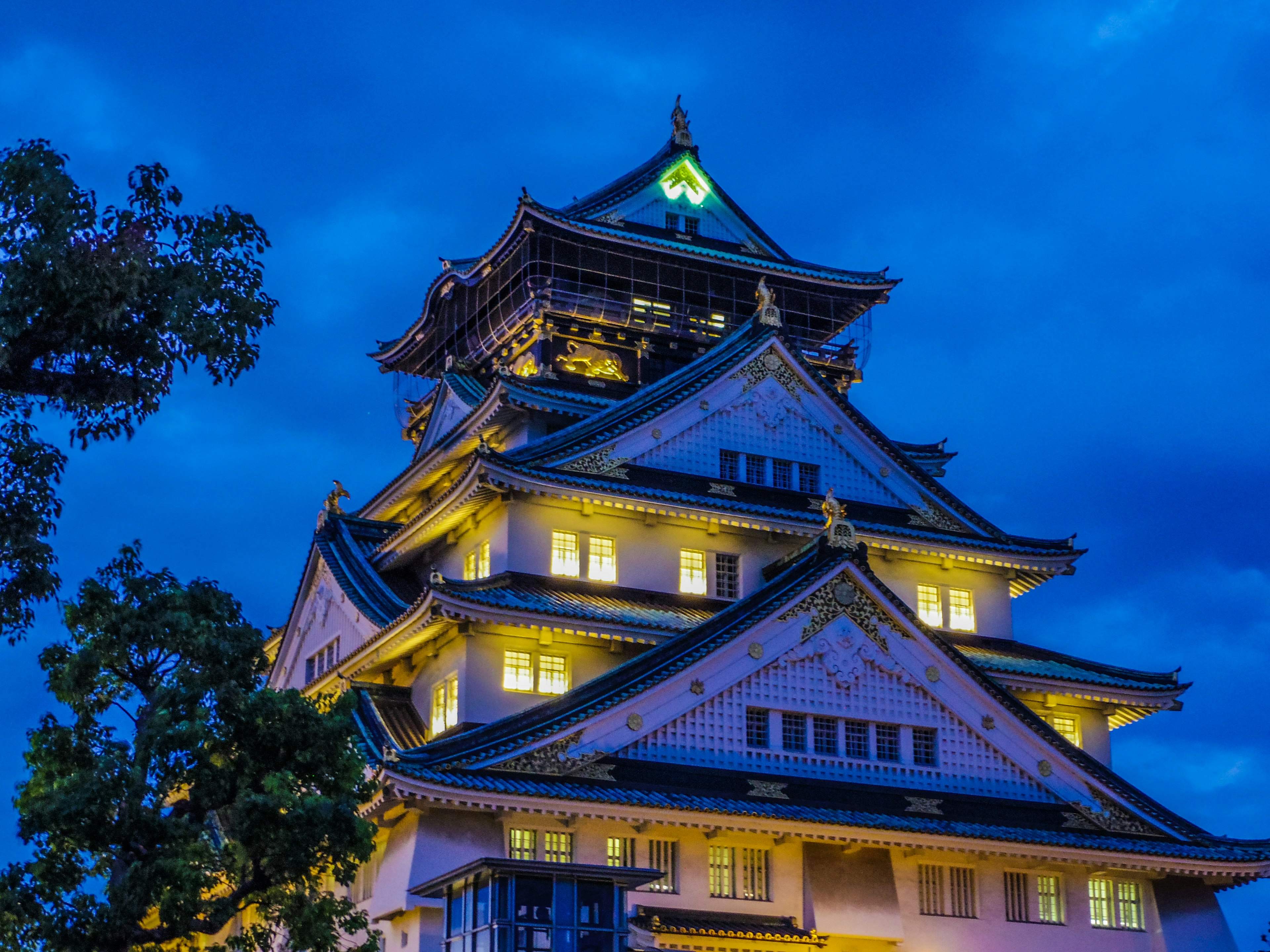 A beautiful night view of Osaka Castle with illuminated features against a blue sky