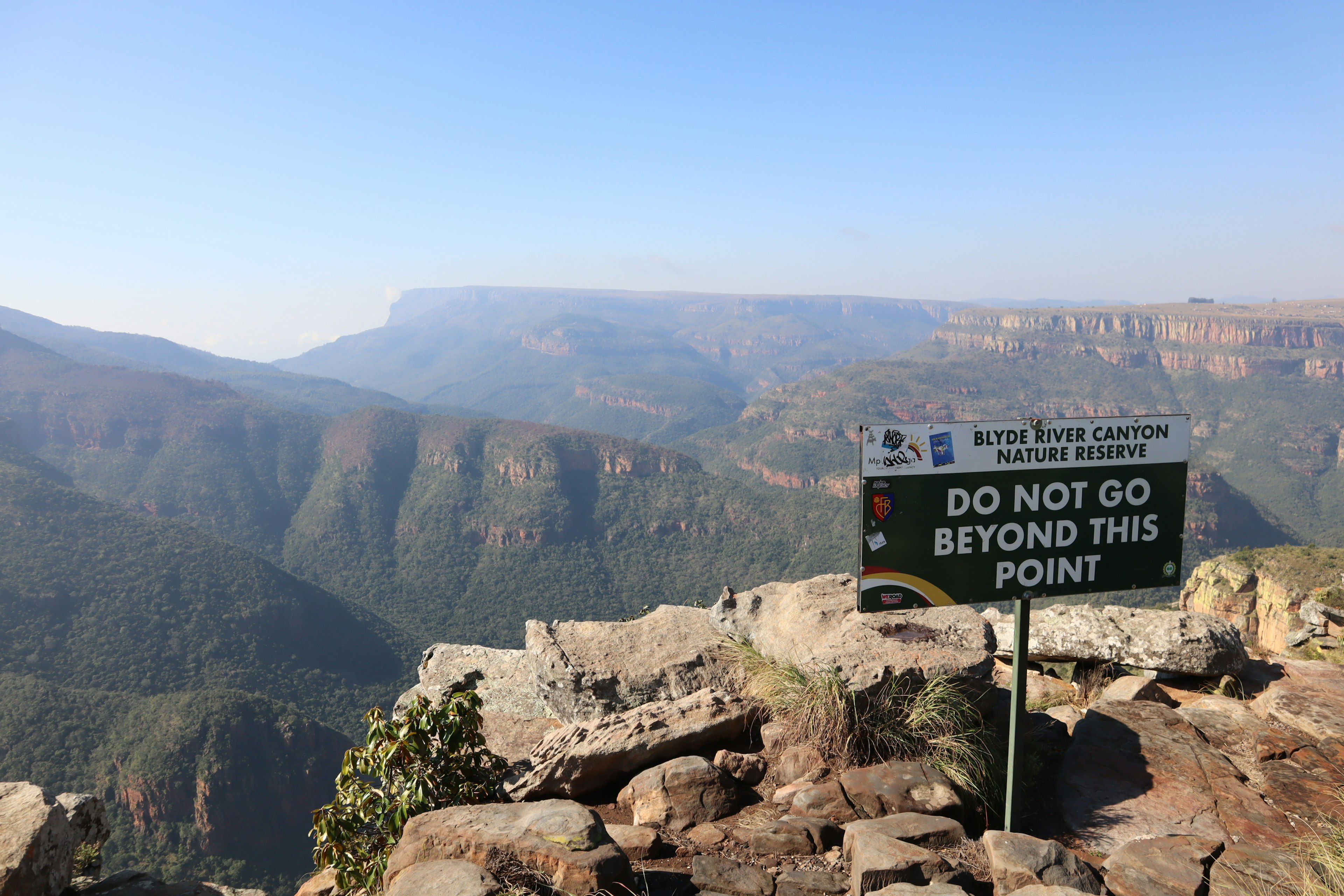 Sign warning not to go beyond this point with a vast mountain landscape