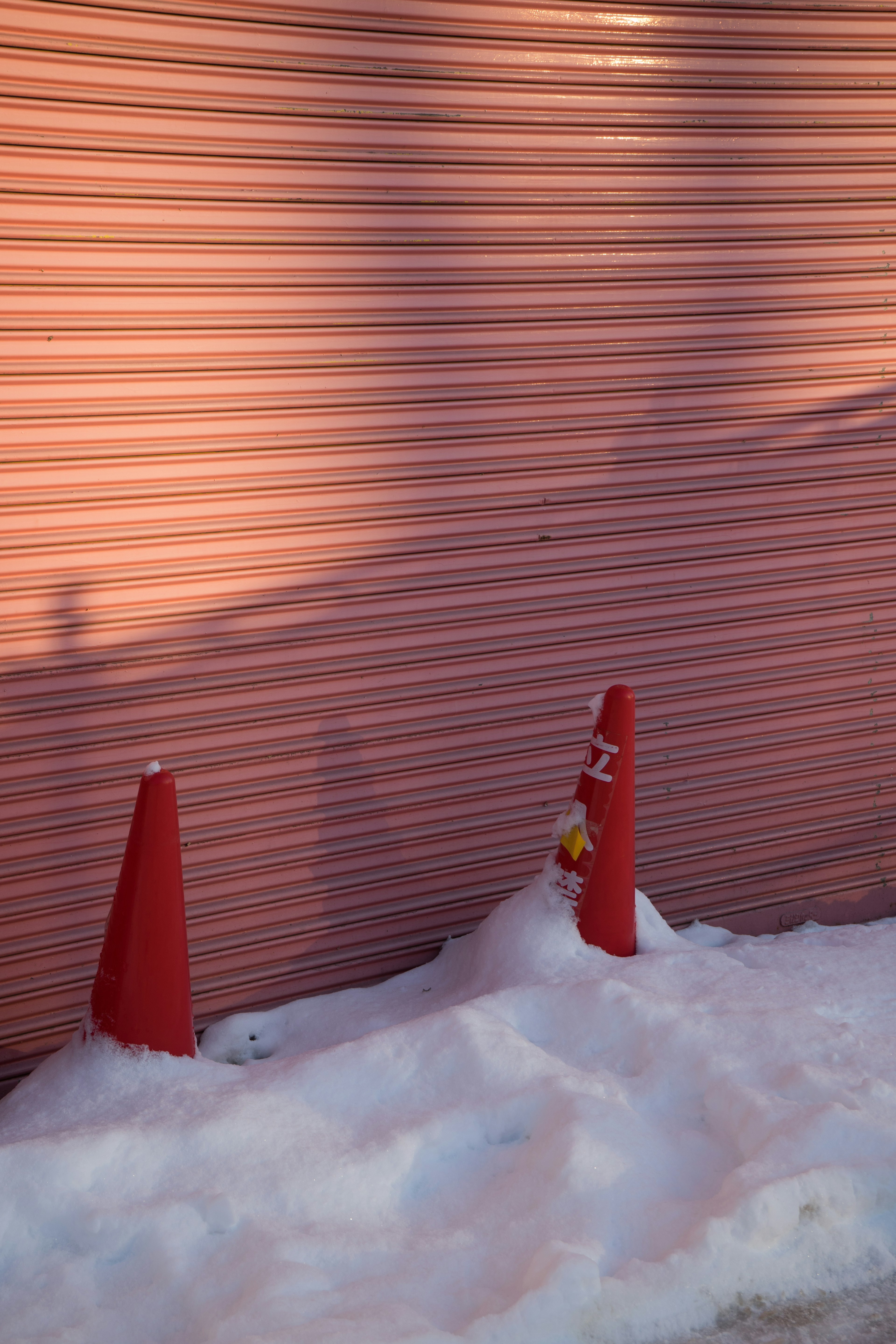 Red cones in snow against a textured wall