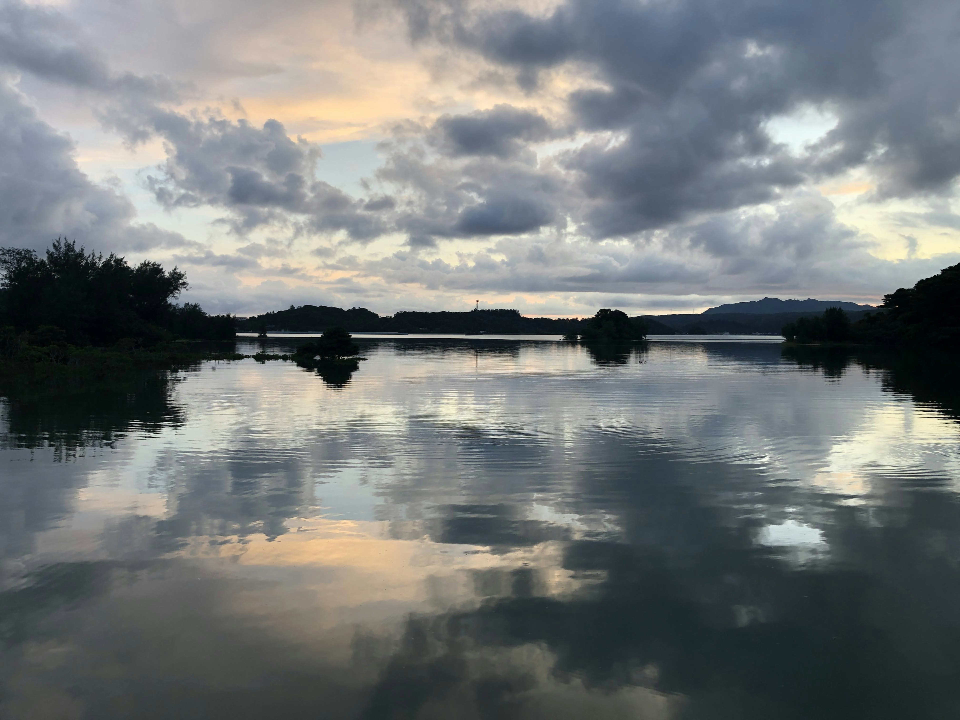 静かな湖面に映る雲と夕焼けの色合い