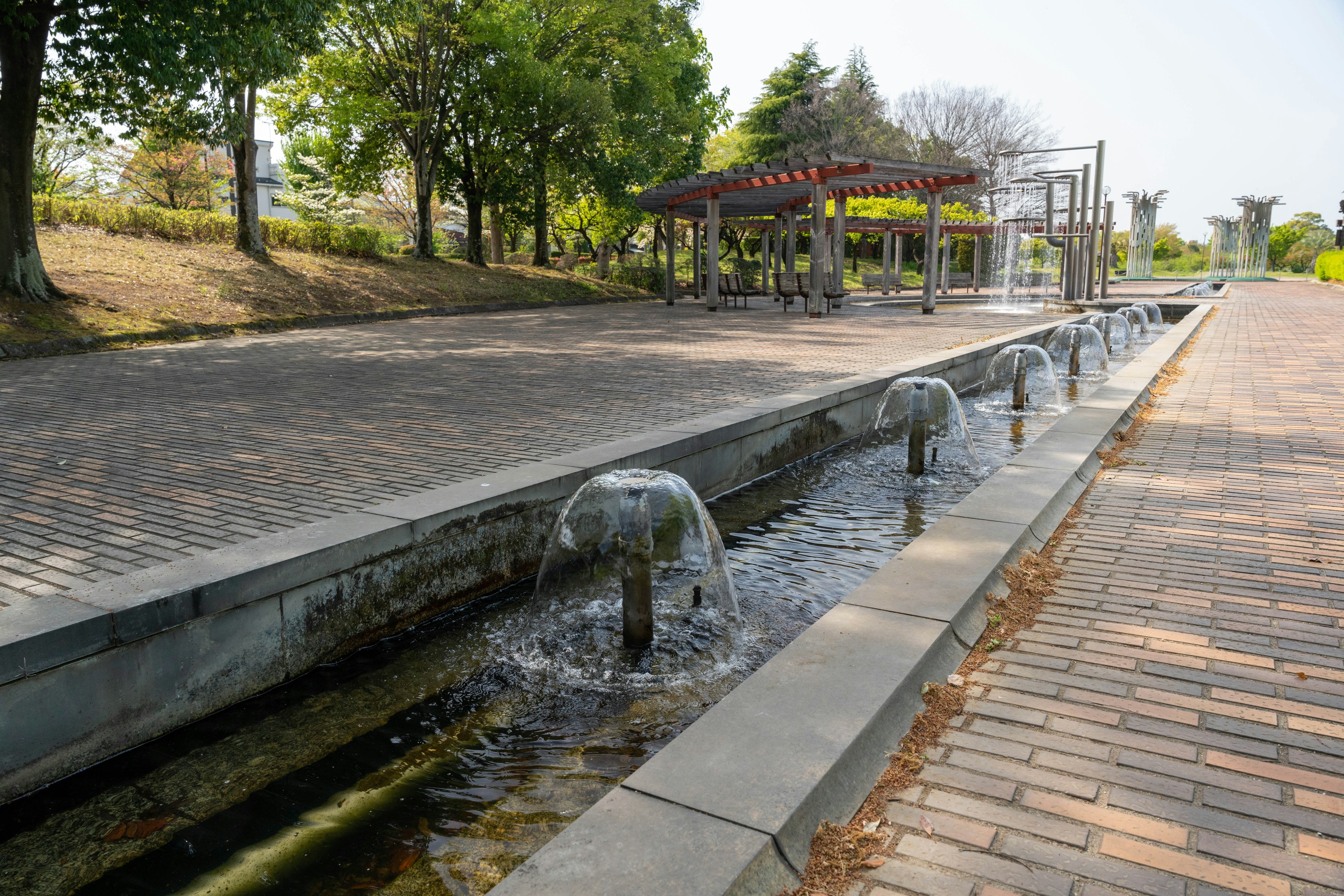 Parkszene mit Wasserfluss und Spielbereich