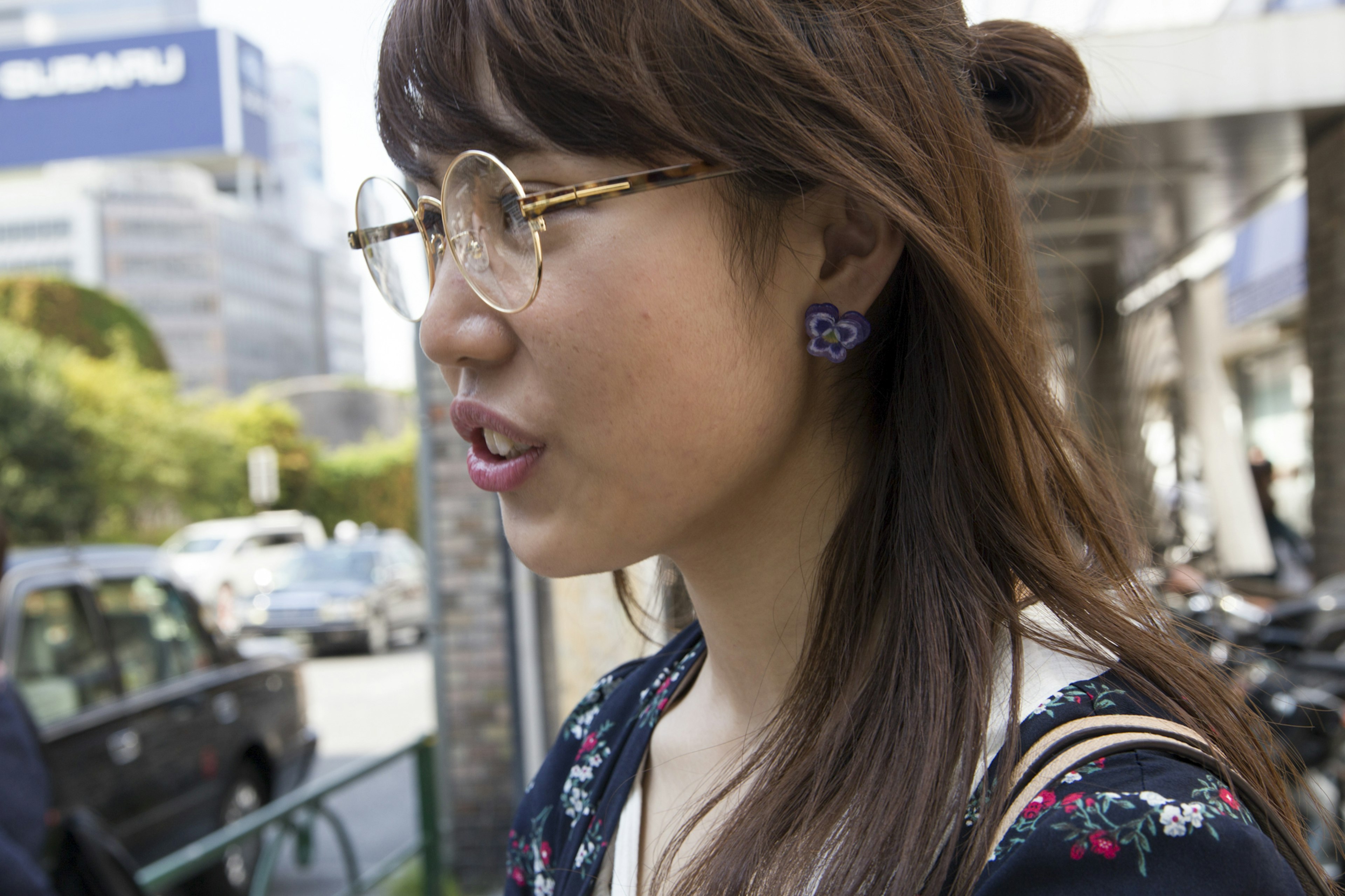 Woman with glasses seen from the side wearing purple earrings