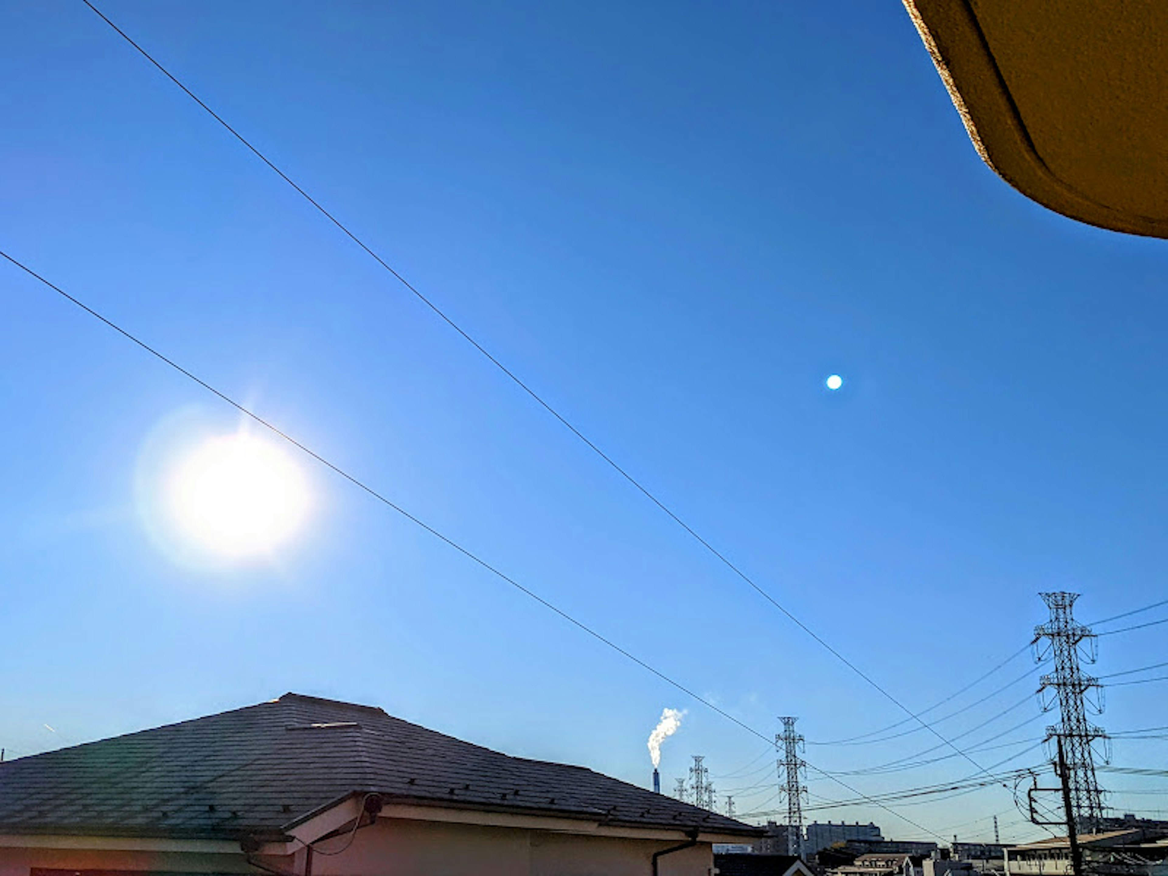 Clear blue sky with the sun and a chimney visible